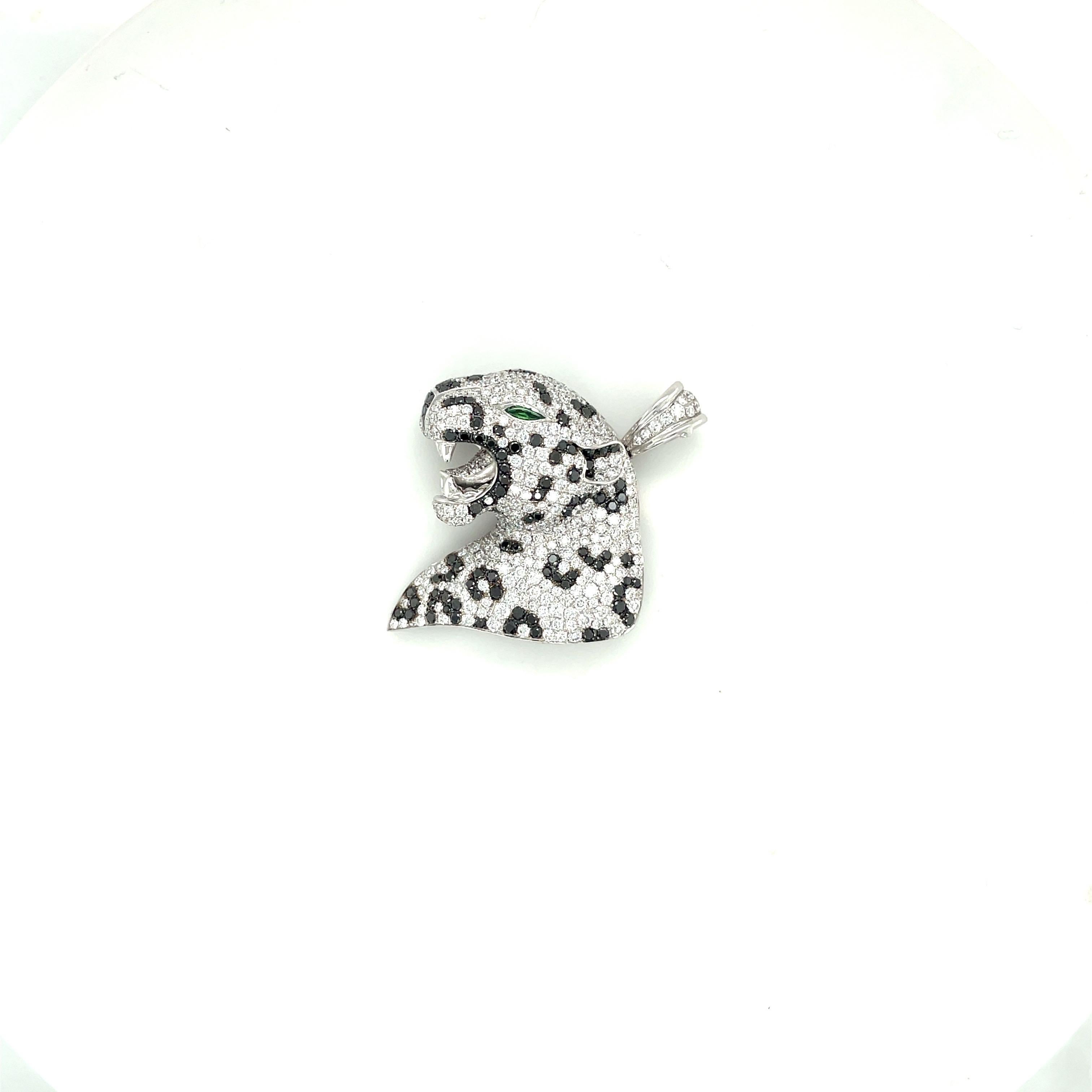This fierce 18 karat white gold panther pendant is meticulously set with black and white round brilliant diamonds. His eye is a marquis tsavorite stone. The panther measures 1.25