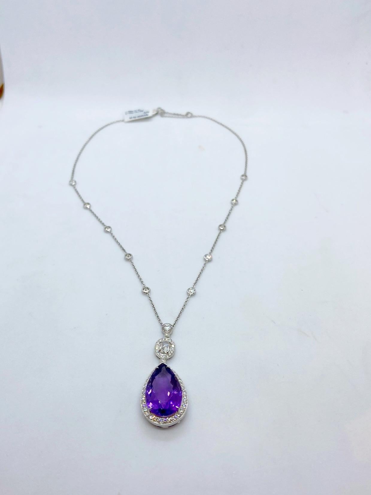 Cellini Jewelers NYC 18 karat white gold pendant is designed with a pear shaped Amethyst  drop set in a Diamond bezel. The center  Amethyst stone is joined with an oval rose cut  and a round rose cut Diamond. Both are set in Diamond bezels. The drop