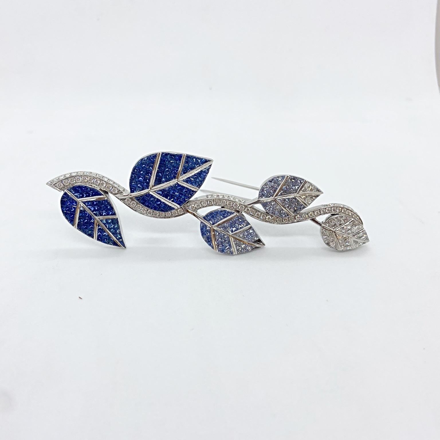 An extraordinary set 18 karat white gold , Diamond and Blue Sapphire leaf brooch. Each of the five leaves are invisibly set with Princess Cut stones. The top leaf starts in all white Diamonds slowly following to shaded colors of Blue Sapphires . The