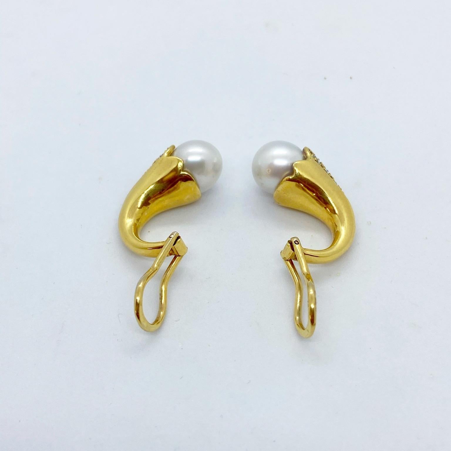 A very classic and wearable earring. These 18 karat yellow gold clip on earrings are set with round brilliant diamonds and topped with south sea pearls. The earrings measure 1