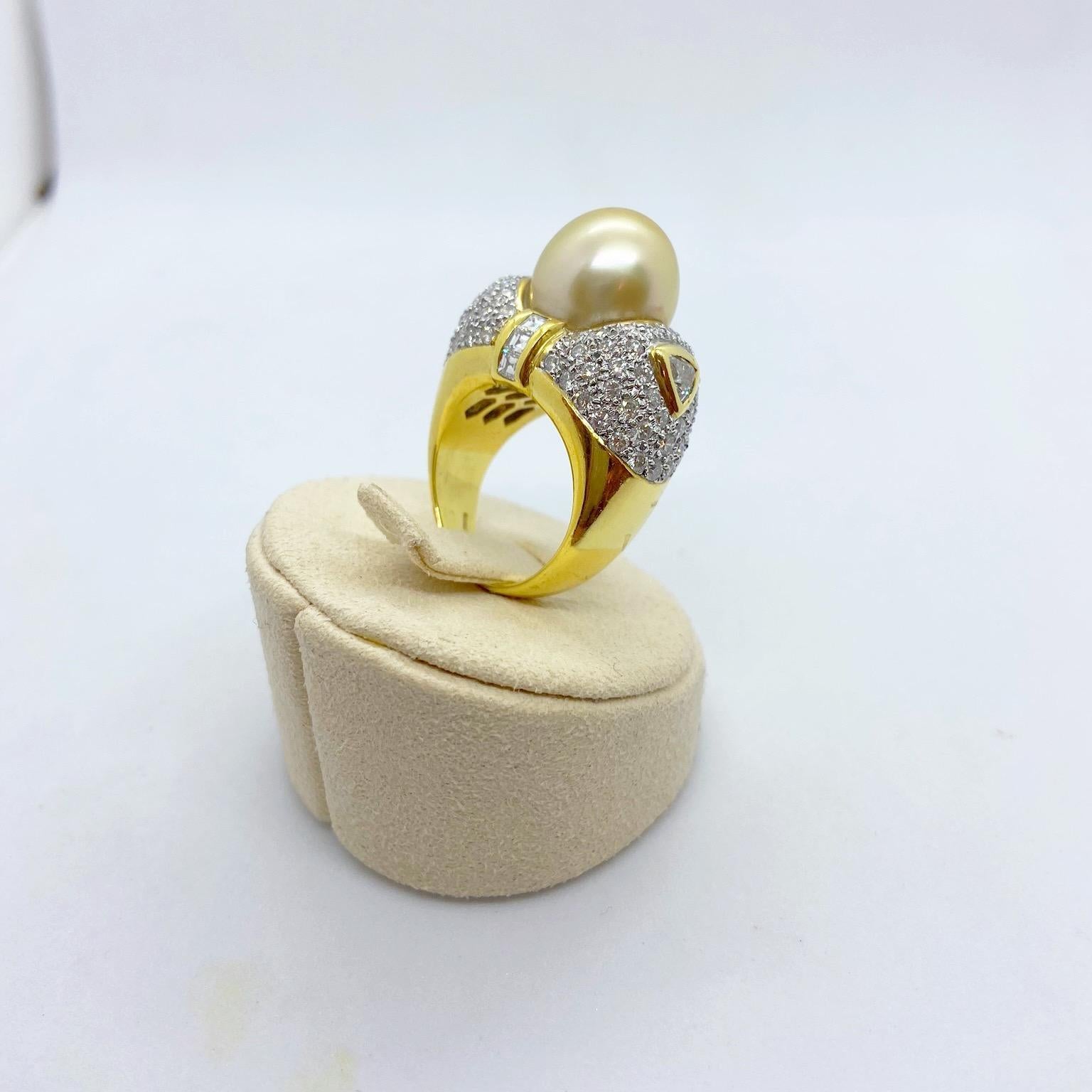 Cette bague magnifiquement conçue par Cellin Jewelers NYC, présente une magnifique perle d'or des mers du Sud de 13,2 mm, qui est détaillée avec des trillions et des émeraudes carrées sertis en chaton, entourés de diamants ronds brillants. Le poids