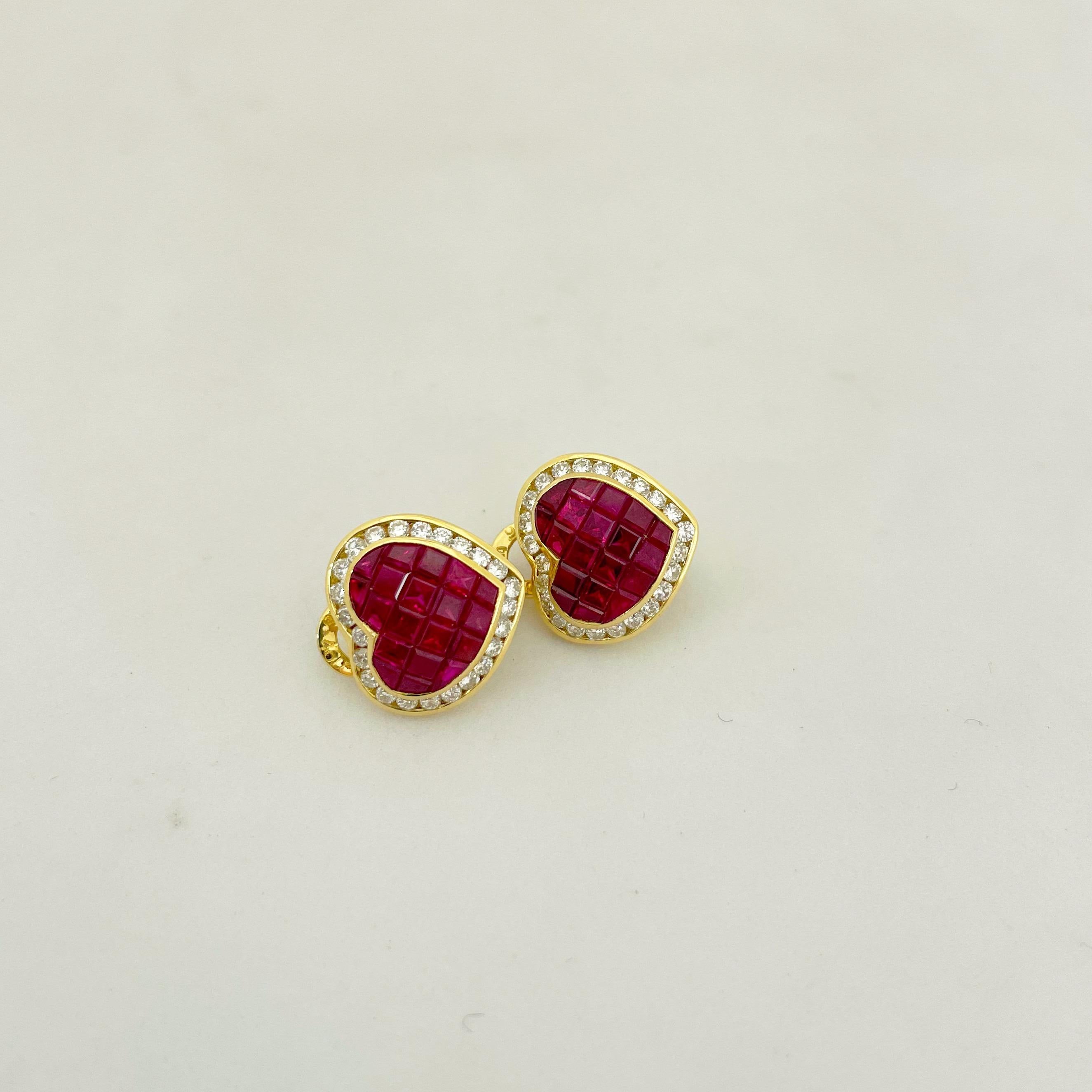 Cellini 18 karat yellow gold heart shaped earrings. These earrings are set with 5.20 carats of square cut rubies which have been invisibly set. A yellow gold bezel set with 1.30 carats of round brilliant diamonds frame the rubies in these beautiful