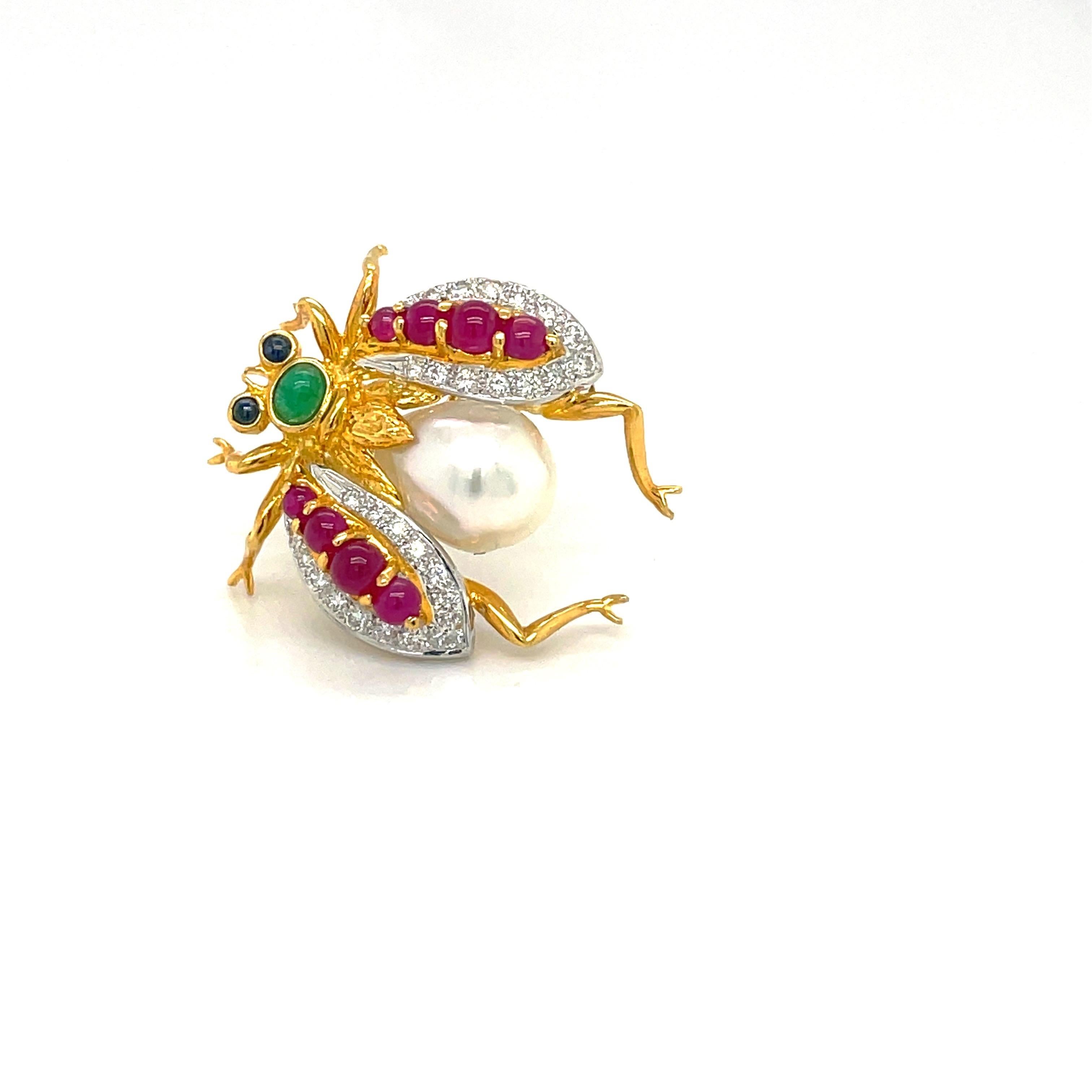 A beautifully designed 18 karat yellow gold bee brooch. The bee's wings are set with round brilliant diamonds and cabochon rubies. The body is set with a 12 x 8.5 mm South Sea Pearl . The  head and eyes are cabochon emerald and blue sapphire. The