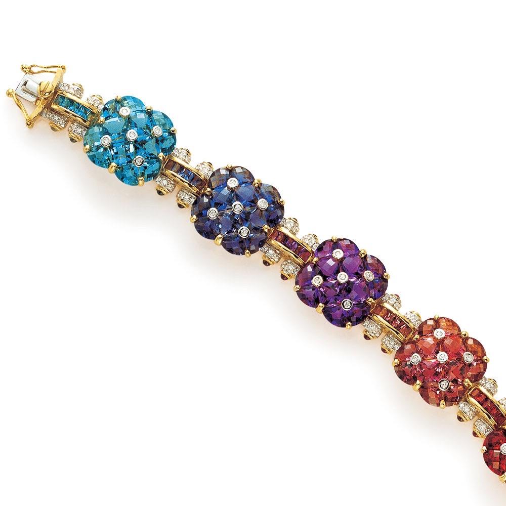 This Cellini Jewelers NYC, 18 karat yellow gold bracelet is set with Peridot, Green and Pink Tourmaline, Citrine, Garnet, Amethyst, Iolite and Blue Topaz. Each section is a grouping of stones forming a clover shape and highlighted with white gold