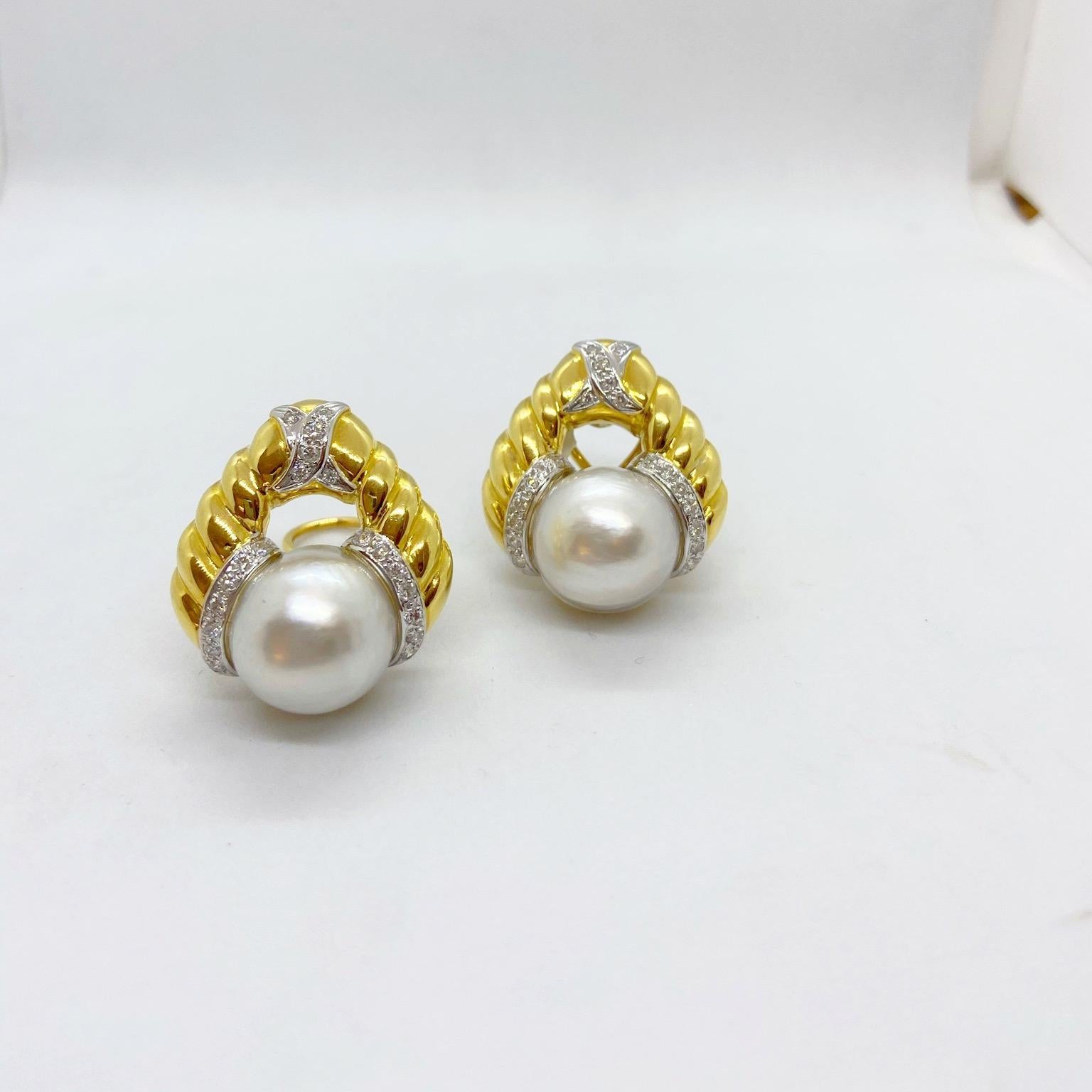 Classic 18 karat yellow gold clip on earrings by Cellini Jewelers NYC. The earrings feature large South Sea pearls with white gold diamond accents. The earrings measure 1.25