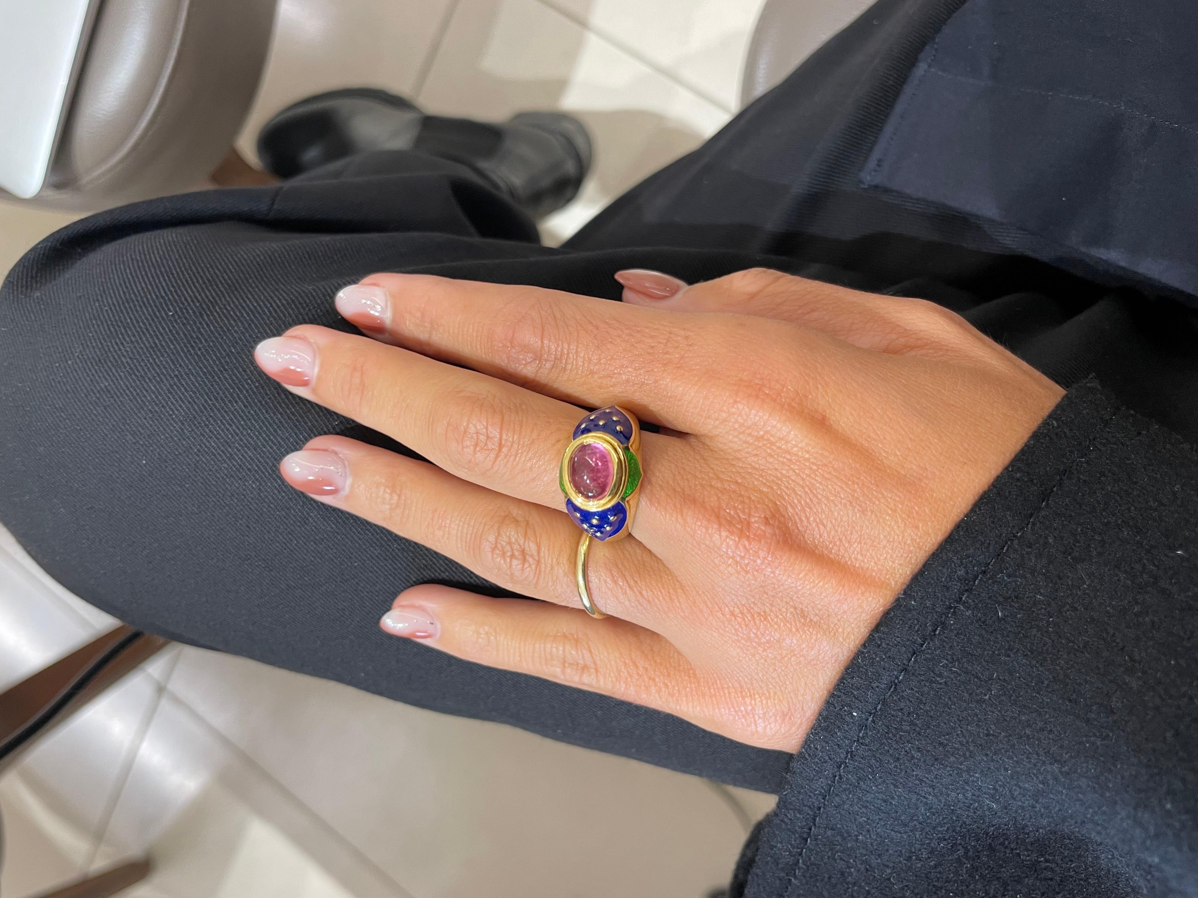 Lovely 18 karat yellow gold ring designed with the intention of a flower. The ring centers an oval cabochon pink tourmaline set horizontally. Green and blue enamel accent the center stone.
Ring size 7.5
Stamped Cellini 750