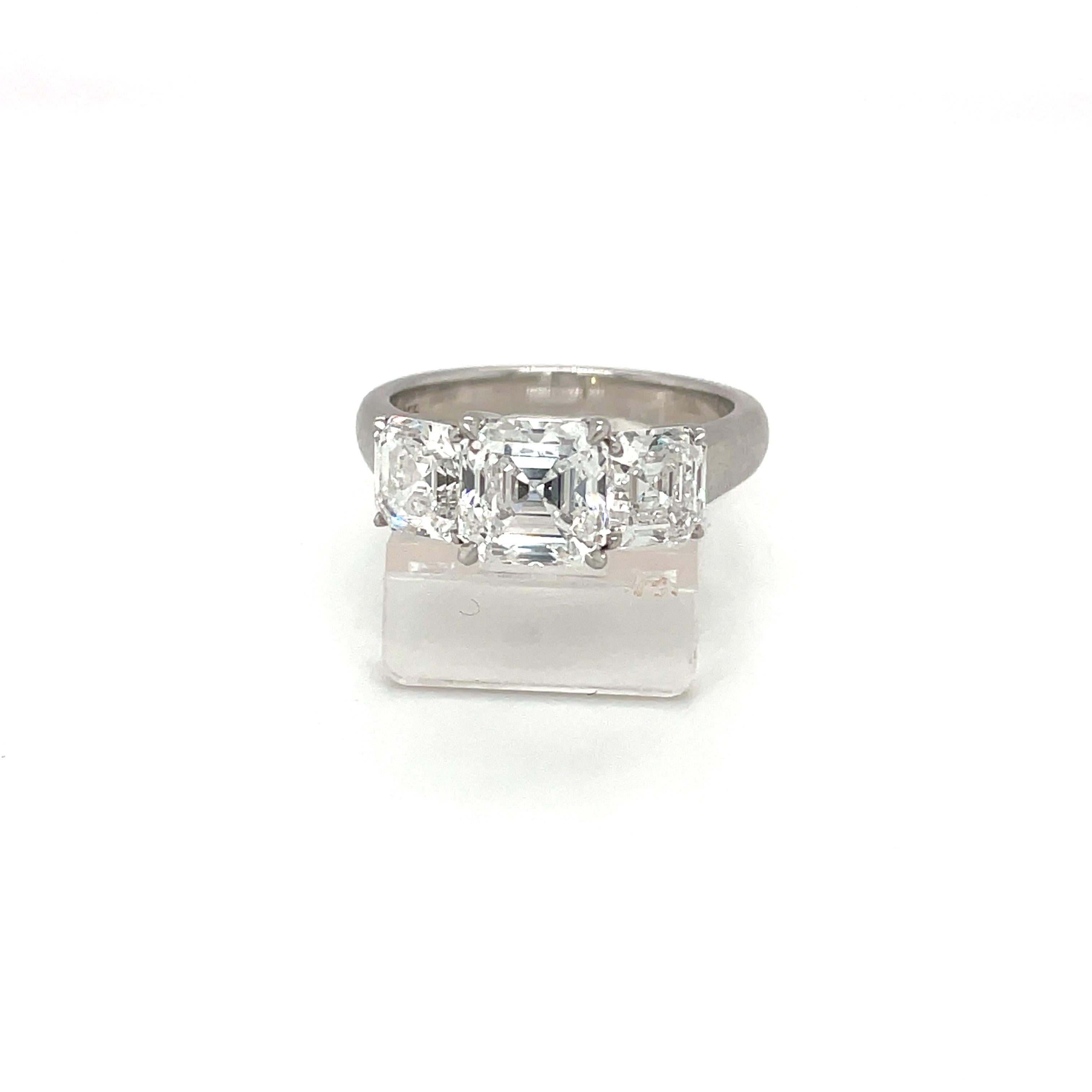 Cette bague classique et enchanteresse présente un diamant émeraude carré de 1,59 carat de couleur E et de pureté VVS2.... Sertie dans une bague traditionnelle à trois pierres avec des émeraudes carrées parfaitement assorties, de 0,82 carat chacune,