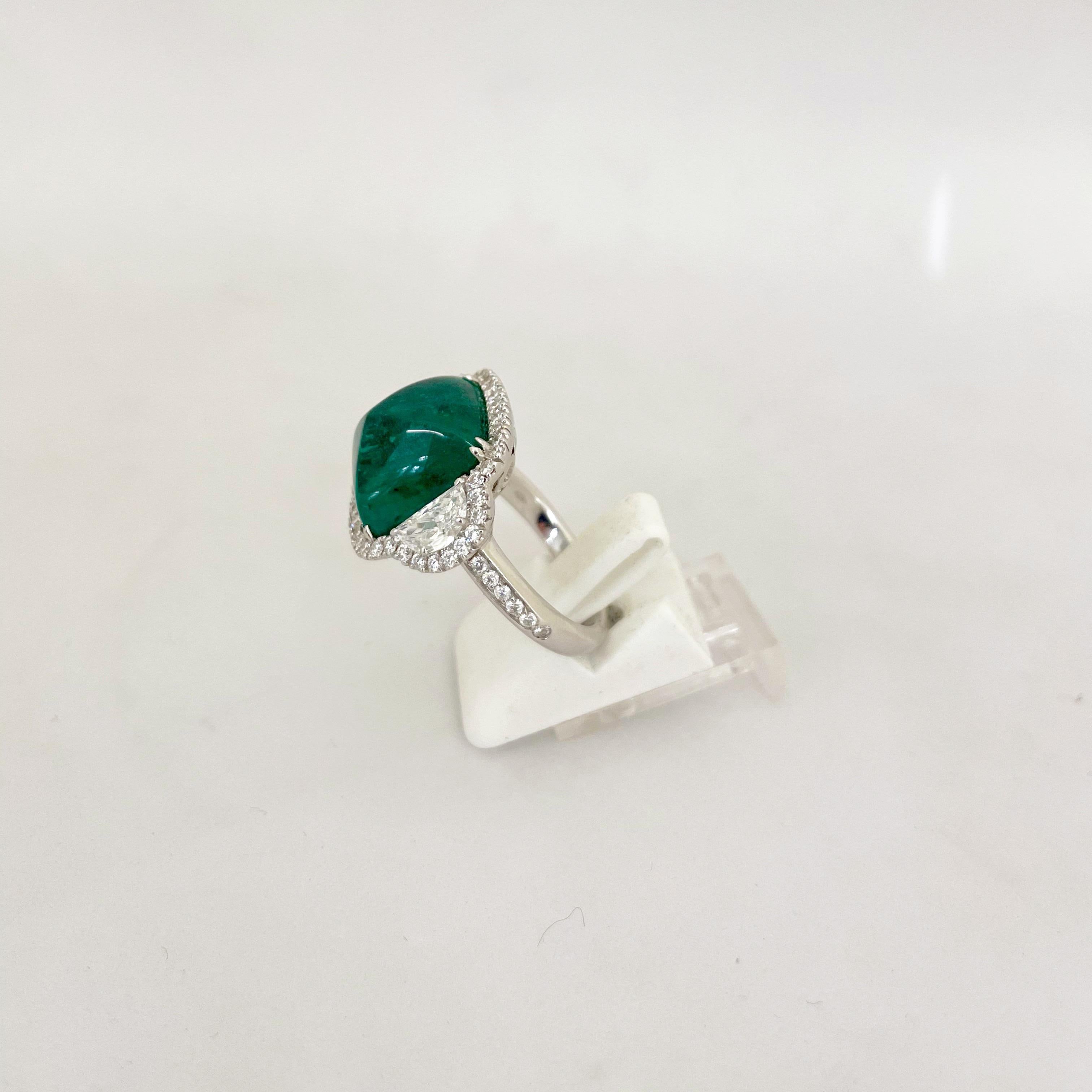 This truly show stopping sugarloaf cabochon emerald is flanked by half-moon diamonds and surrounded by a micro-pave diamond bezel, with diamonds on the shank of the ring. 
The emerald is 10.58 ct 
Half moon diamonds total 0.84cts 
Round diamond
