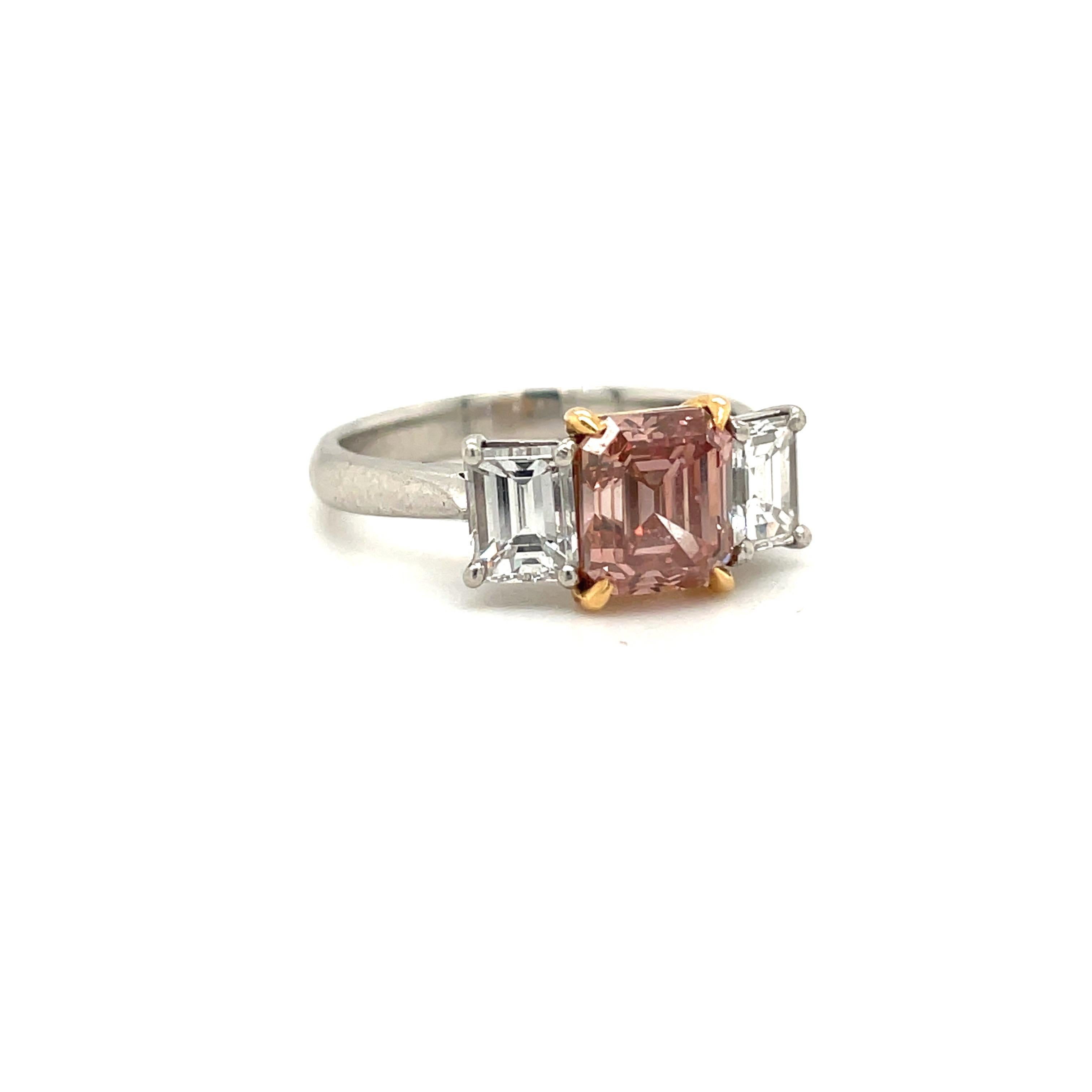 Natural, GIA certified fancy brownish-orange-pink emerald-cut diamond mounted with emerald-cut white diamond side stones; in a platinum and 18-karat rose gold setting.
Truly one of a kind, this rare fancy pink diamond is made even more special due
