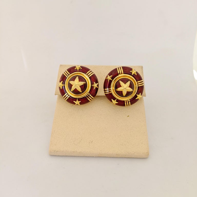 Cellini Jewelers NYC, 18 karat yellow gold large round button earrings designed with red guilloche enamel and applied with star shaped gold details. The earrings are pierced with a post and French clip but can be adjusted for non pierced ears. They