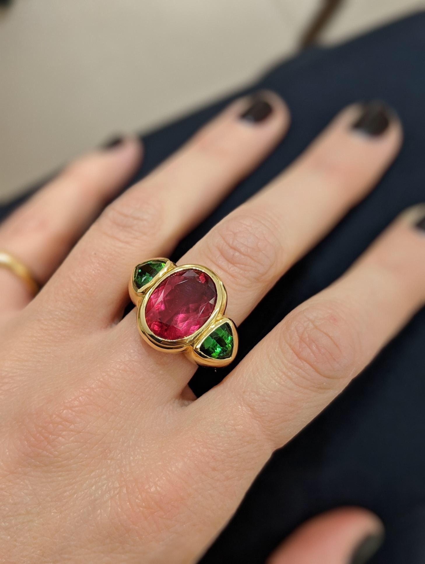 One of a kind, handmade ring exclusively for Cellini Jewelers In NYC. This 18kt yellow gold high polished ring features a magnificent Oval Rubellite weighing  7.27 carats in the center, flanked by a pair of Green Tourmaline Trillions weighing 2.38