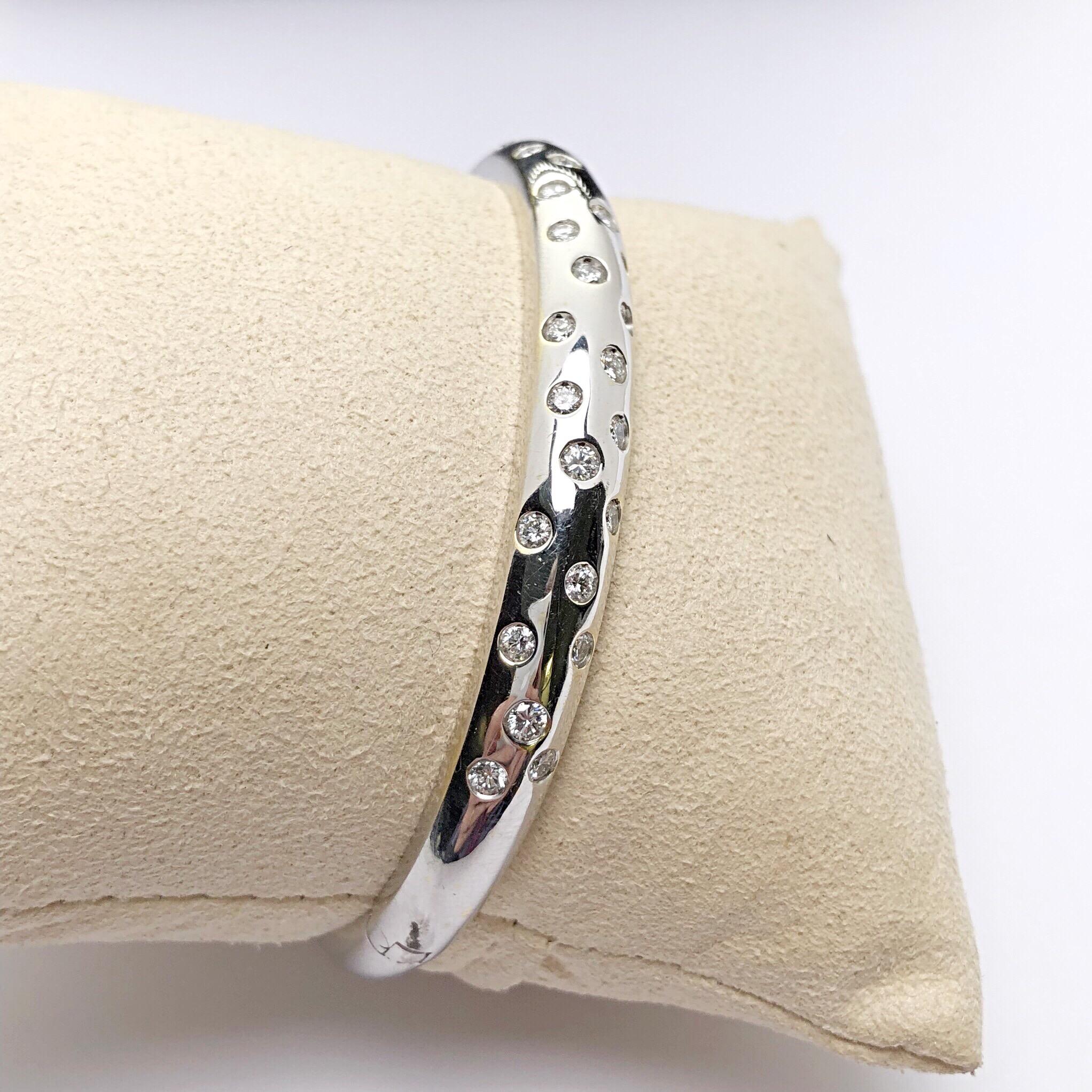 This beautiful high polished 18 KT. white gold bangle, Designed by Cellini Jewelers NYC is sprinkled with  27 round brilliant diamonds. The diamonds are of various weights totaling 1.10 carats.
The bangle is an oval shape, designed to fit on the