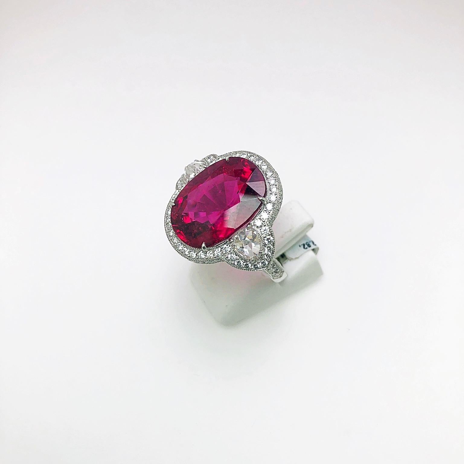 This stunning 12.82 carat oval cut rubelite ring is beautifully set in between two pear shape rose cut diamonds, which are surrounded by a flat wire micro-pavé setting.The setting is designed with a heart scroll on both sides of the shank. 
Rubelite