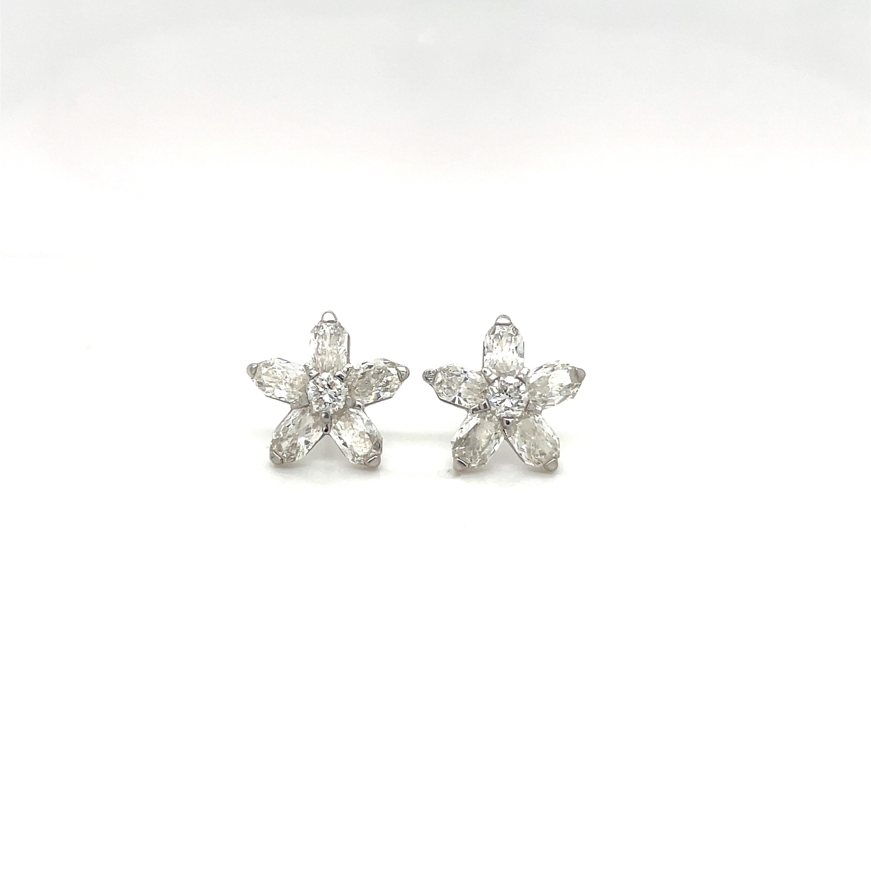 Féminin et élégant est la meilleure façon de décrire ces boucles d'oreilles en forme de fleur en diamant. La fleur est composée de 5 coupes fantaisie  pétales de diamant et 1 diamant rond brillant au centre .  Ils se situent dans  or blanc 18