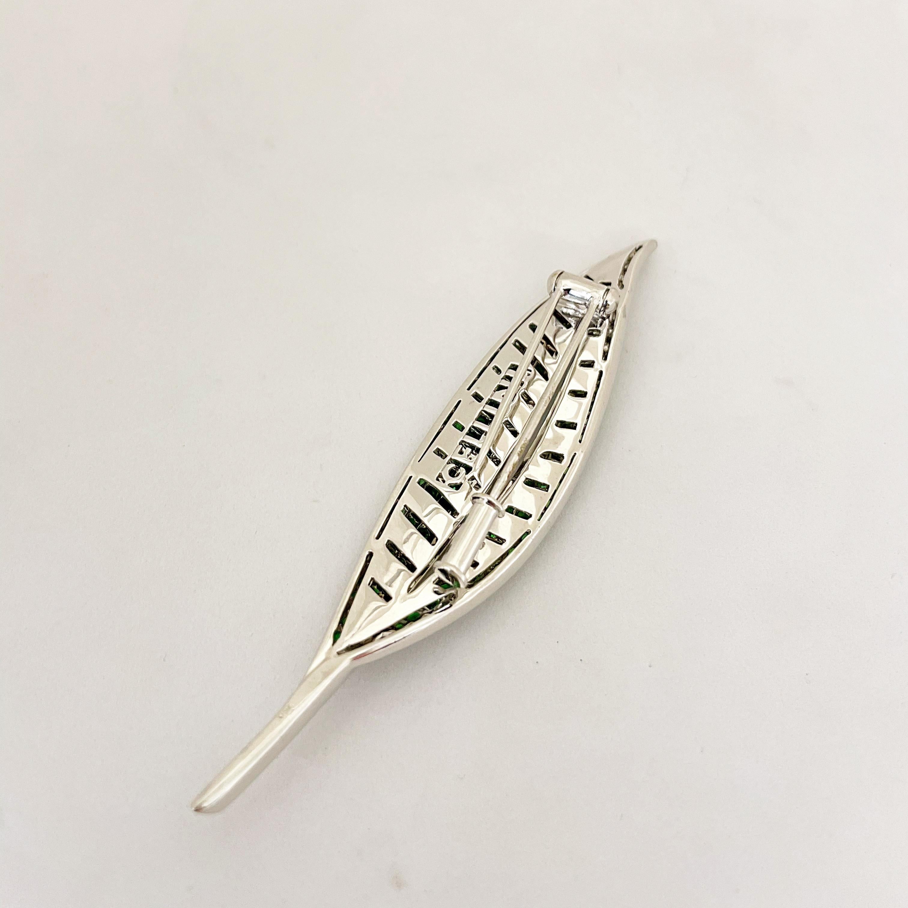 Cellini Jewelers NYC beautiful leaf brooch. This slender 18 karat white gold leaf brooch is beautifully set with ombre round tsavorite stones. The stem is set with round brilliant diamonds. The leaf measures 3.50