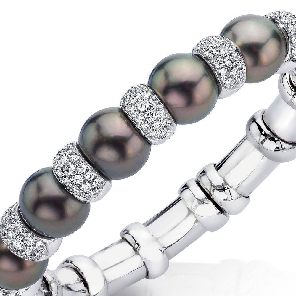 Flexibler Armreif mit schwarzen Tahiti-Perlen, besetzt mit weißen Diamanten und gefasst in 18 Karat Weißgold.
Das Innenmaß des Armbands ist 2 5/8