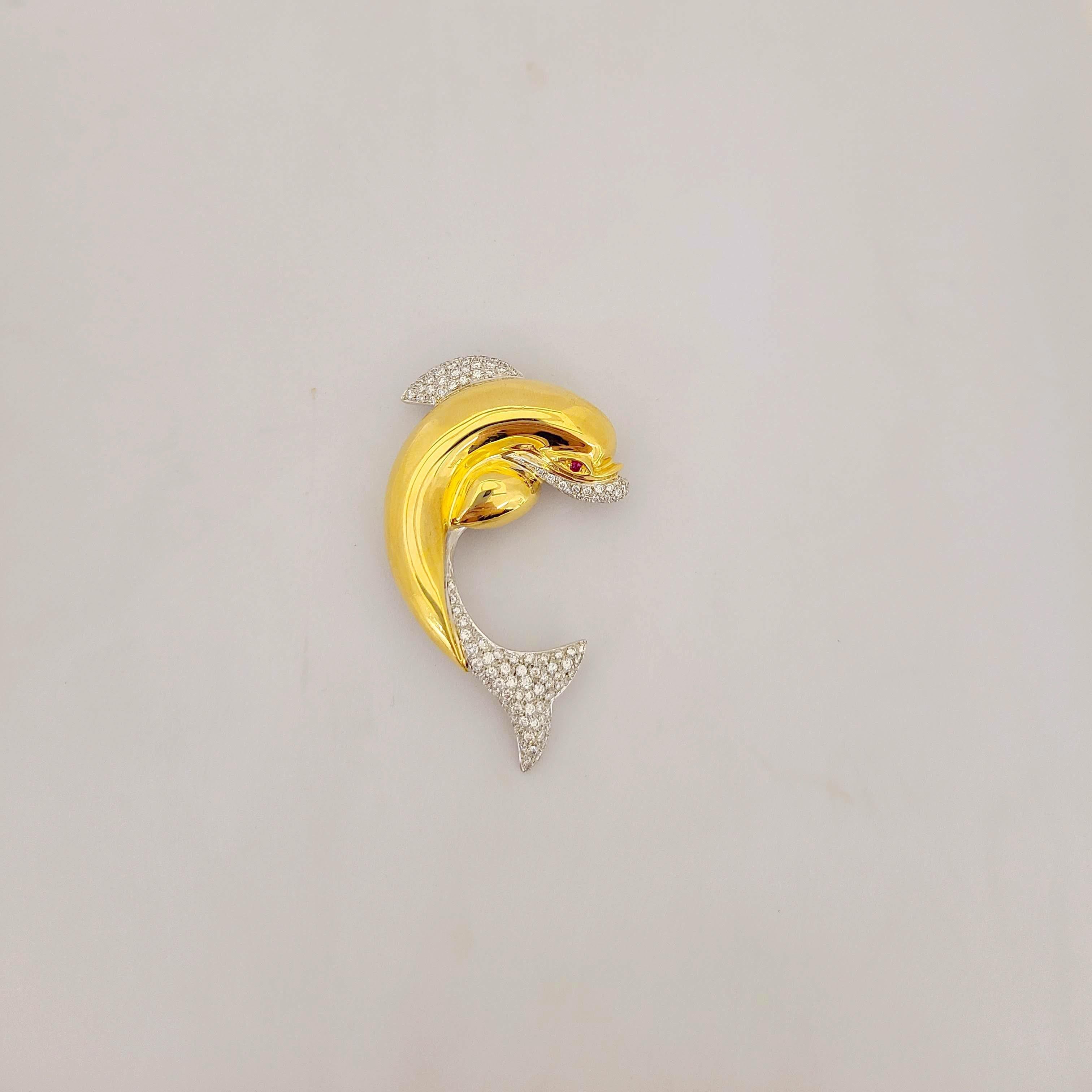 Cellini 18 karat yellow gold dolphin brooch. Designed in a hi polished yellow gold ,beautifully set with pave diamond in the tail, fin and mouth. A brilliant cut ruby is set for the eye. The dolphin measures 2