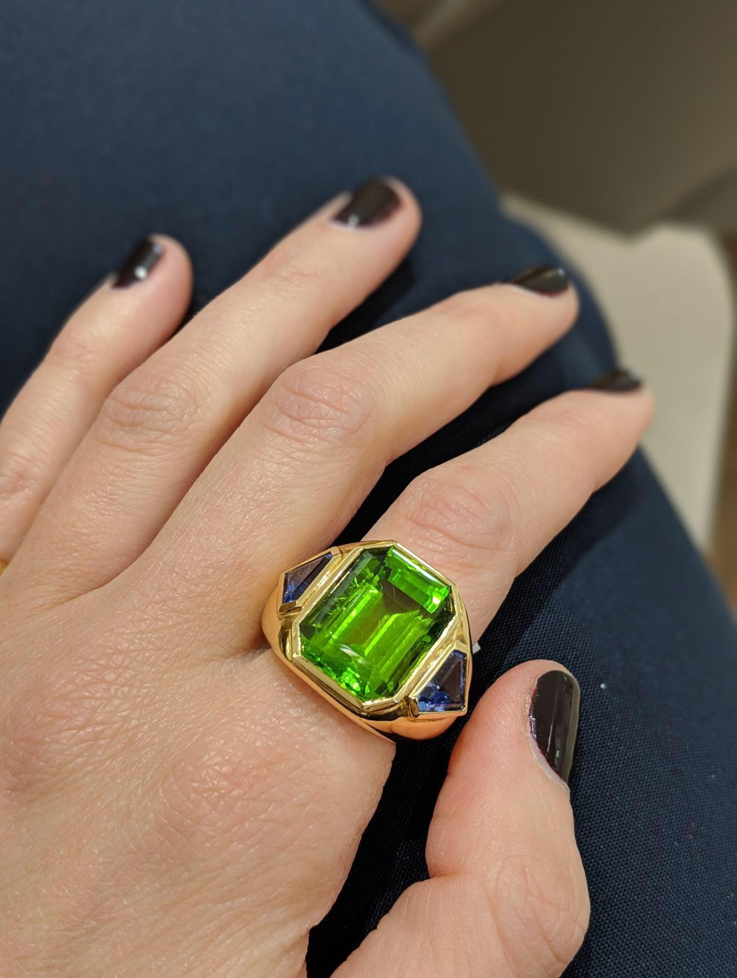 One of a kind, handmade ring exclusively for Cellini. This 18kt yellow gold high polished ring centers a magnificent Emerald cut Peridot weighing 15.22 carats, flanked by a pair of Tanzanite shields weighing 1.87 carats. The ring is designed so that