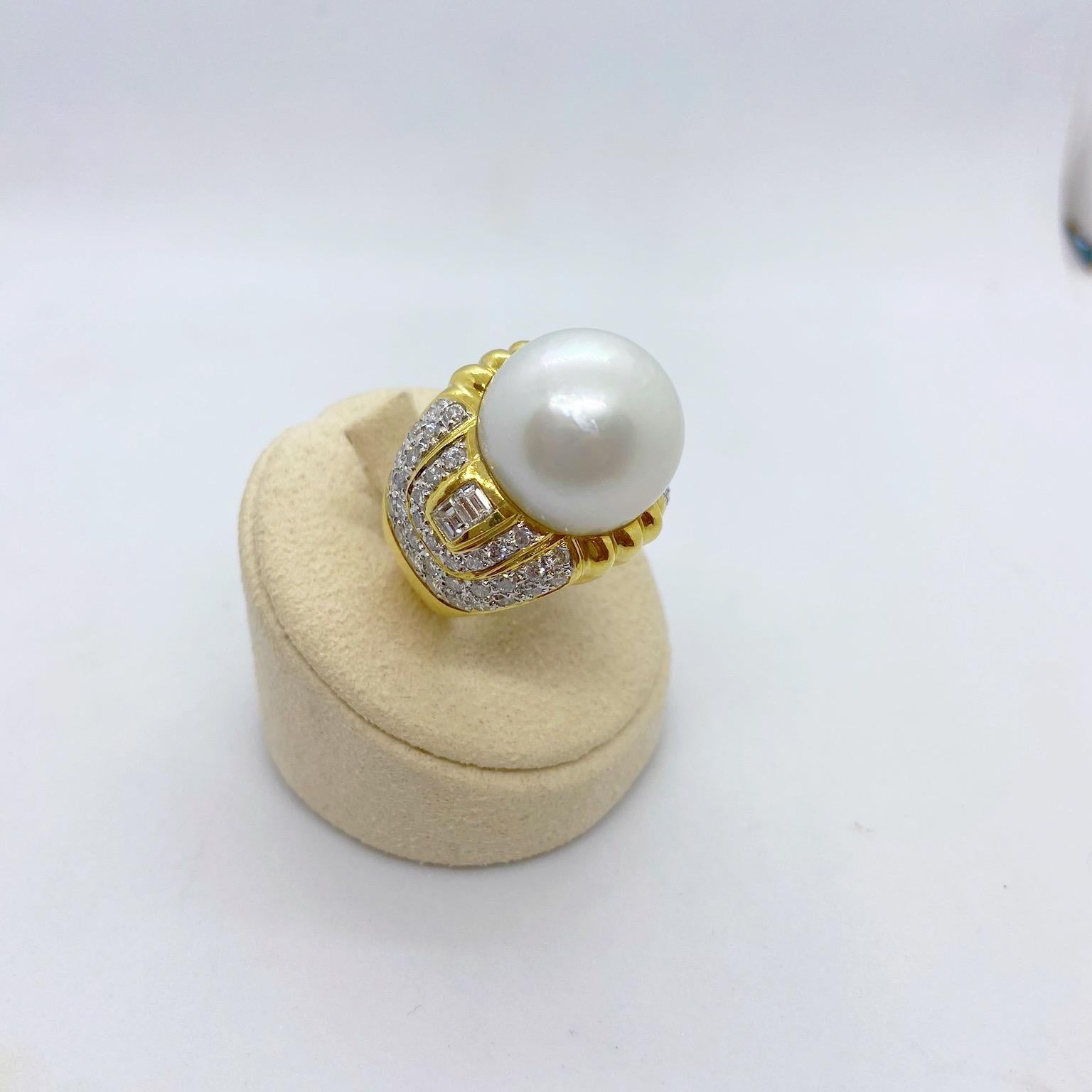 Designed by Cellini Jewelers NYC, This 18 Karat Yellow Gold Deco Inspired Ring features a stunning 16.5MM South Sea Pearl center. The Pearl is flanked with bezel set Emerald cut diamonds, and is surrounded entirely with round brilliants which are