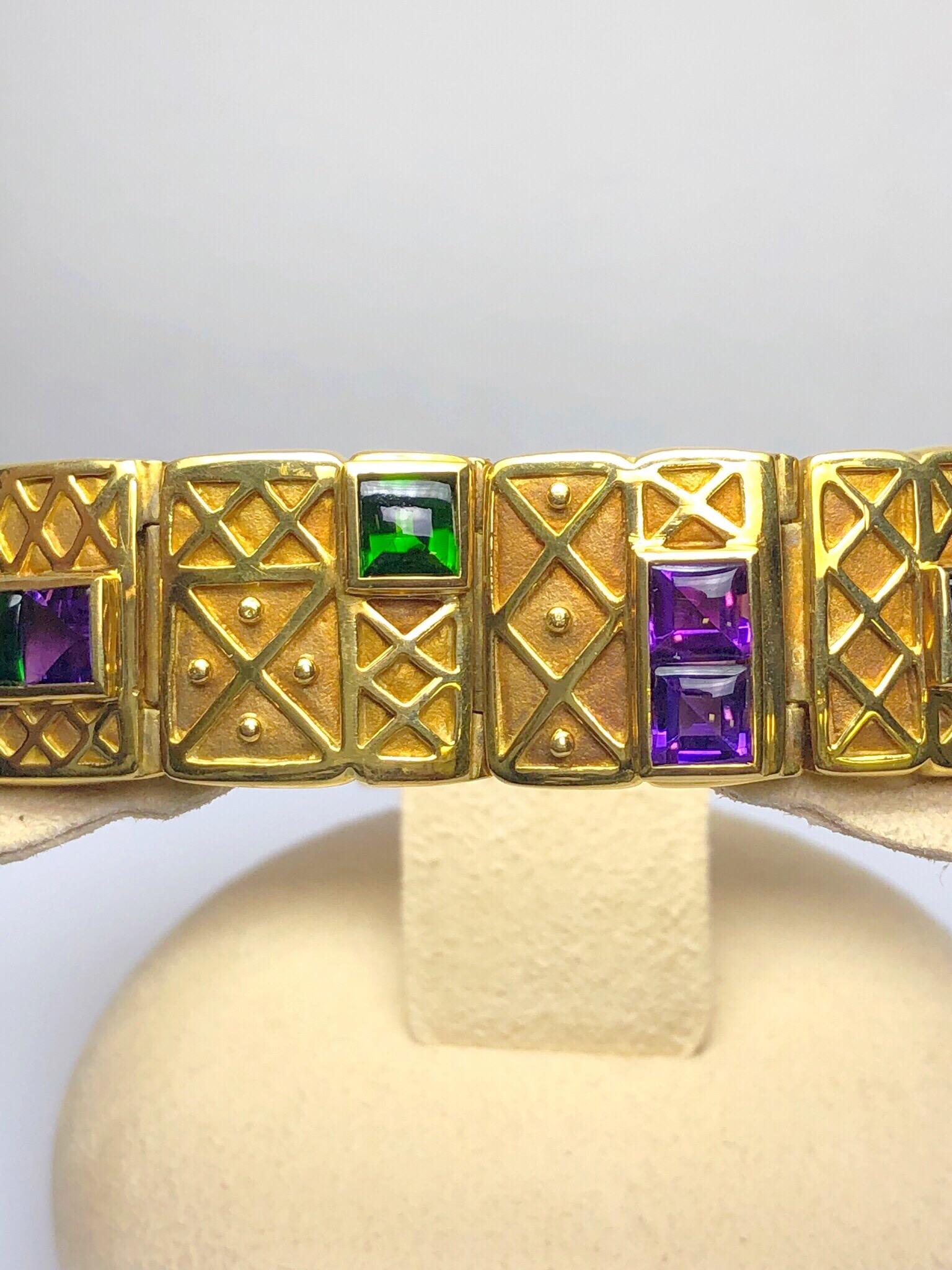 This 18KT yellow gold link bracelet was made for Cellini by Charles Turi. The 12 square links are designed with geometric patterns each set with combinations of French cut Amethyst and Chrome Green Tourmaline. The bracelet measures 7.5