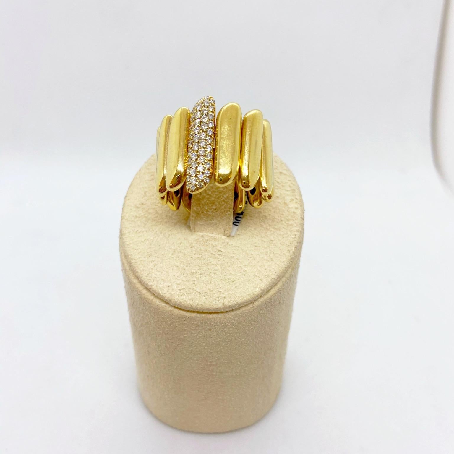 This 18 karat gold ring is designed with shiny yellow gold motifs that are approximately 16.2mm wide. The center motif is set with pave white diamonds. The band type ring is opened in the back allowing for expansion. Fits size 6-9. Matching bracelet