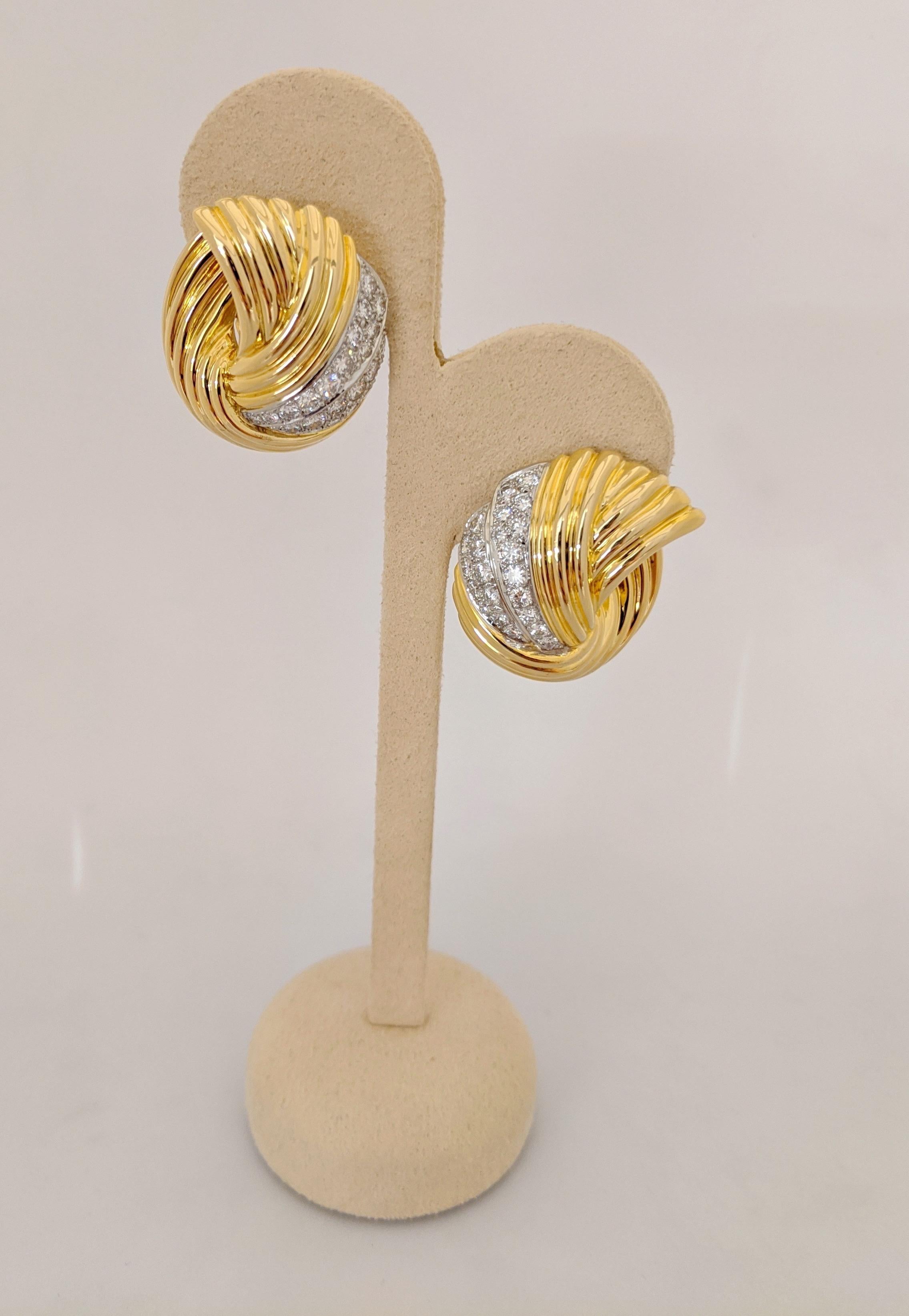 Cellini exclusive 18 karat gold and Diamond earrings. The earrings are designed with a swirl pattern in yellow gold. Each earring has 2 white gold sections that have been set with round Brilliant Cut Diamonds. The earrings measure 1' long x 3/4