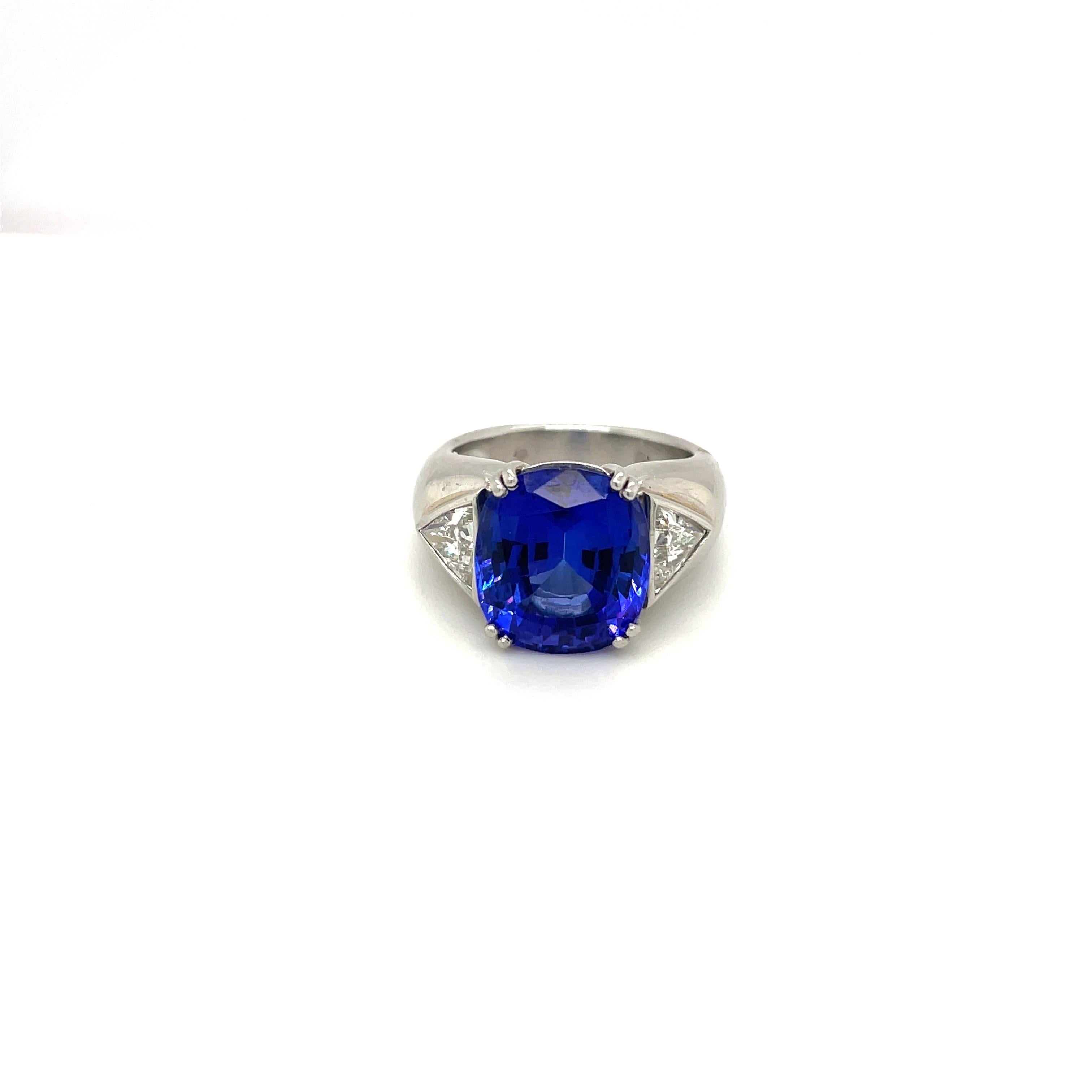 Somewhere between a fiery blue and vibrant violet this rare 9.51ct  tanzanite is set in a unique platinum band with 1.04 its of bezel set trillion cut diamonds. 
The ring is a size 7.75, and can be sized upon request
Appraisal available upon request