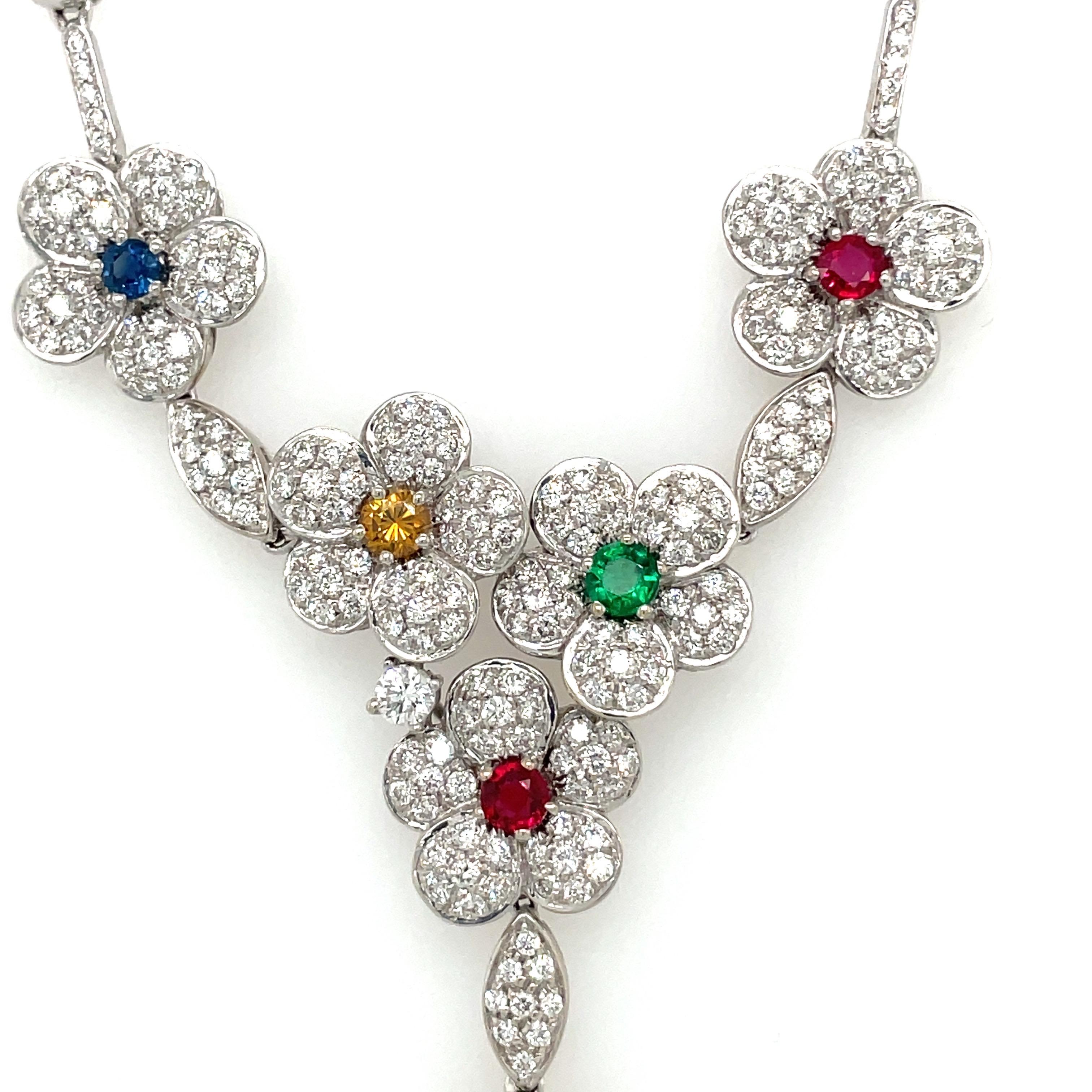 This show-stopping necklaces showcases 6 beautiful diamonds flowers with ruby, emerald, blue and yellow sapphire center stones set in 18 karat white gold. Measuring at about 16