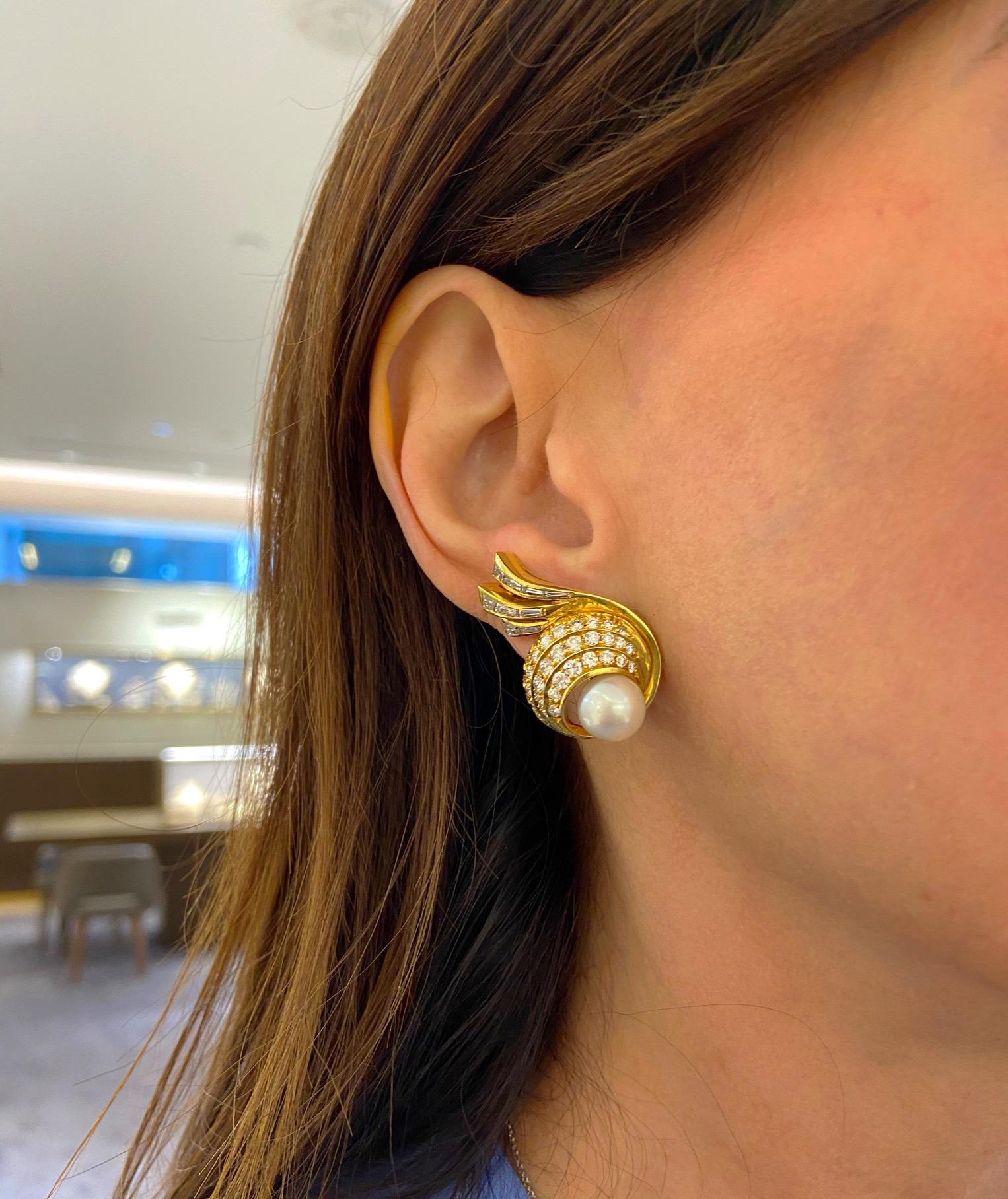 Elegant and classic is the best way to describe these 18 karat yellow gold earrings. The swirl design earrings are set with round brilliant and baguette cut diamonds, which give a nice contrast. The centers are set with 9mm cultured pearls.The