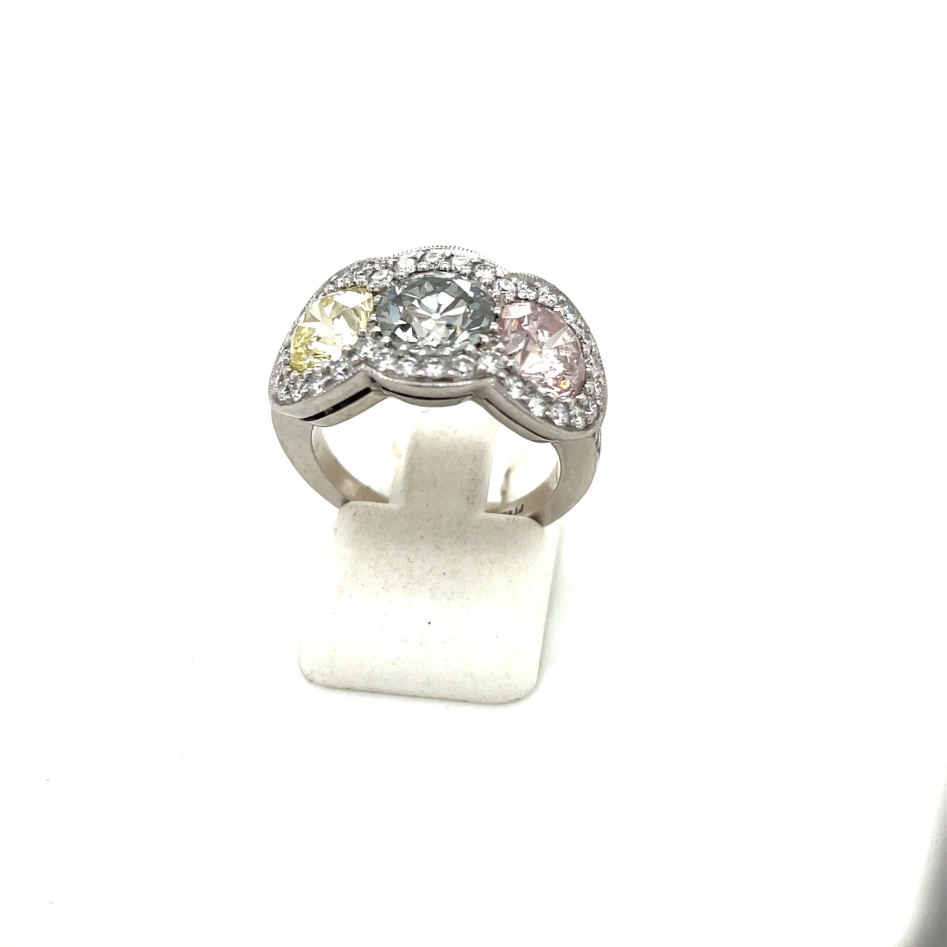 Classic and elegant is the best way to describe this 3 stone fancy colored diamond ring. The 3 brilliant cut pink, yellow and grey diamonds are set in a platinum setting. Each center stone is surrounded by white brilliant cut diamonds. The setting