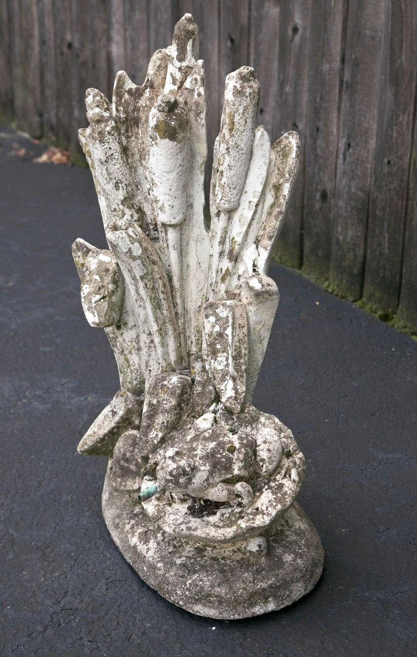 Fontaine à grenouilles en ciment sur un nénuphar.