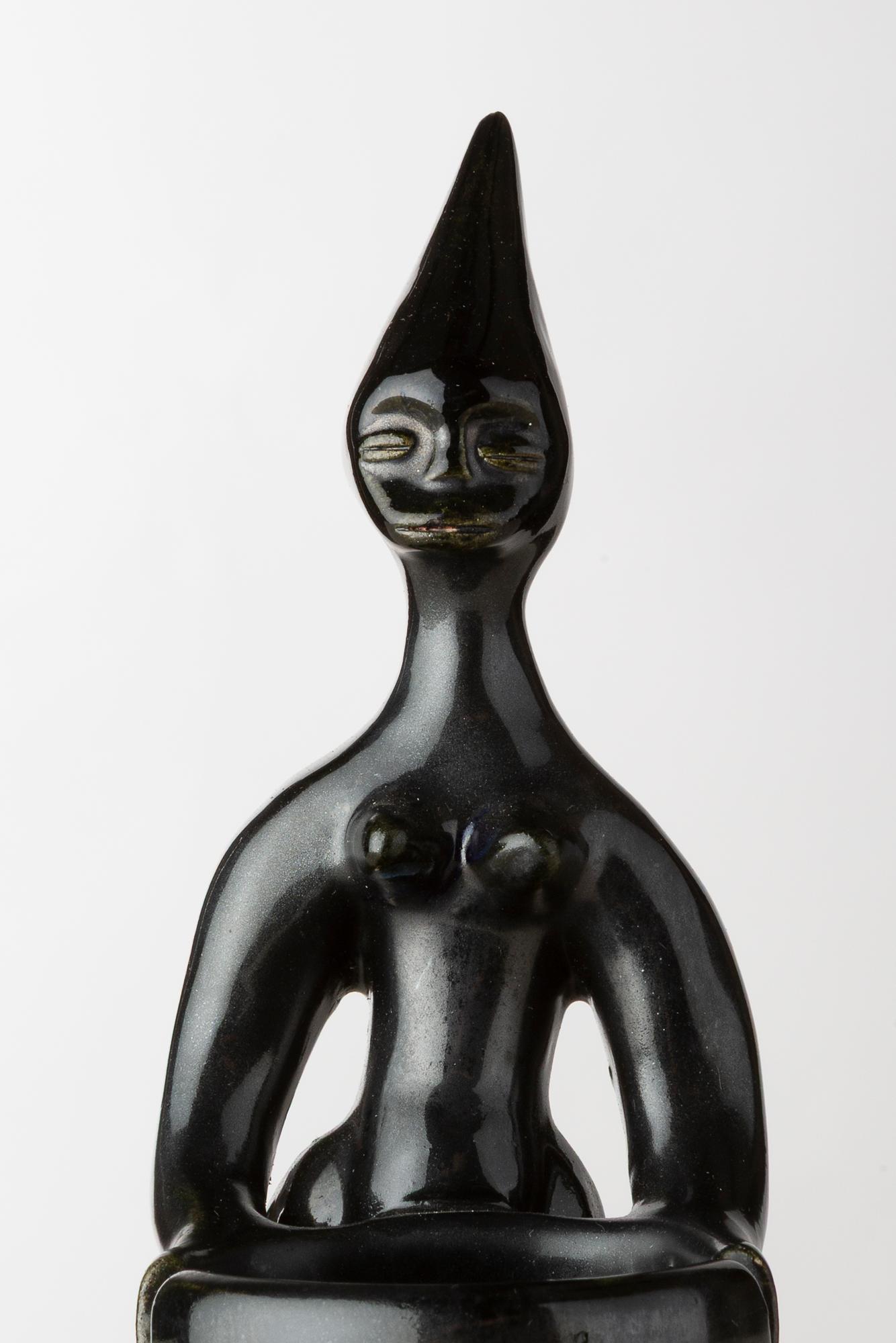Dieser auffällige schwarze Keramik-Aschenbecher des französischen Künstlers Roger Capron zeigt eine stilisierte afrikanistische Figur mit langgestreckten Formen und geometrischen Linien. Die Kombination aus Funktionalität und skulpturaler Eleganz