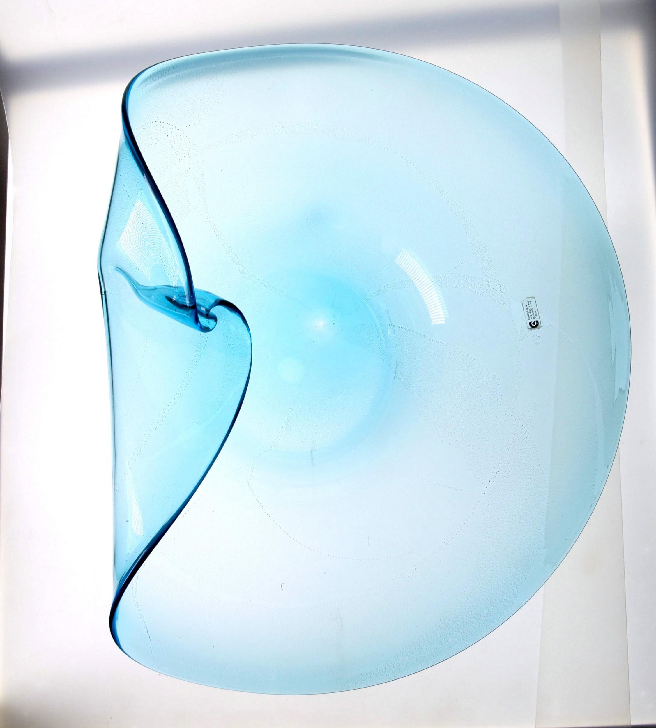 Extraordinary centerpiece in light aquamarine glass with gold leaf. The shape of the bowl has a swirl on the flap that creates an organic play of curves and light. The whole centerpiece becomes a modern sculpture.

Labelled Cenedese Albarelli. I