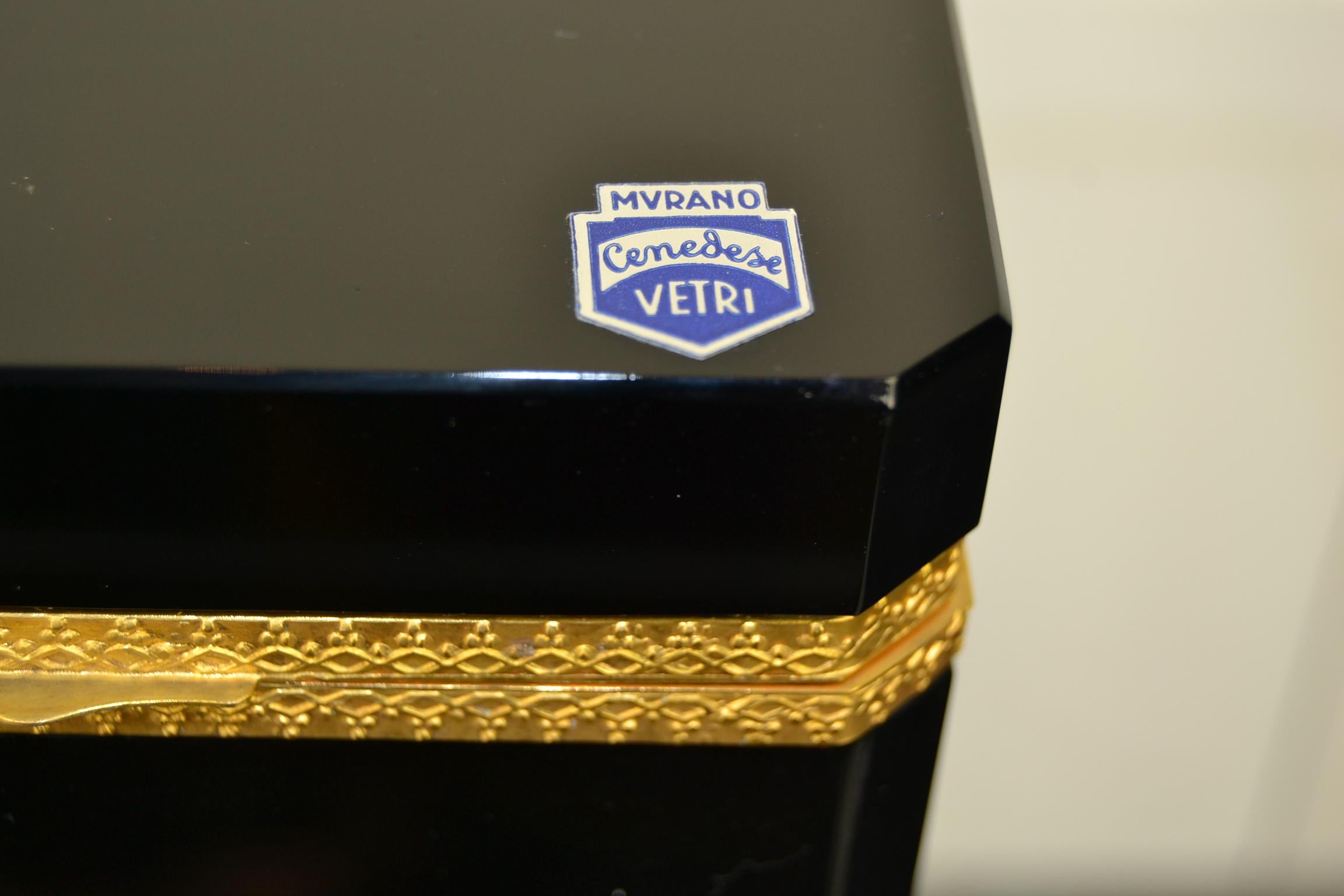 Schwarzes Murano-Schmuckkästchen von Giovanni Cenedese.
Das Etikett befindet sich noch auf dem Deckel: Murano Cenedese Vetri.
Es handelt sich um eine schwarze Dose aus Muranoglas mit vergoldeten Metalldetails, dekorativem Schloss und abgeschrägten
