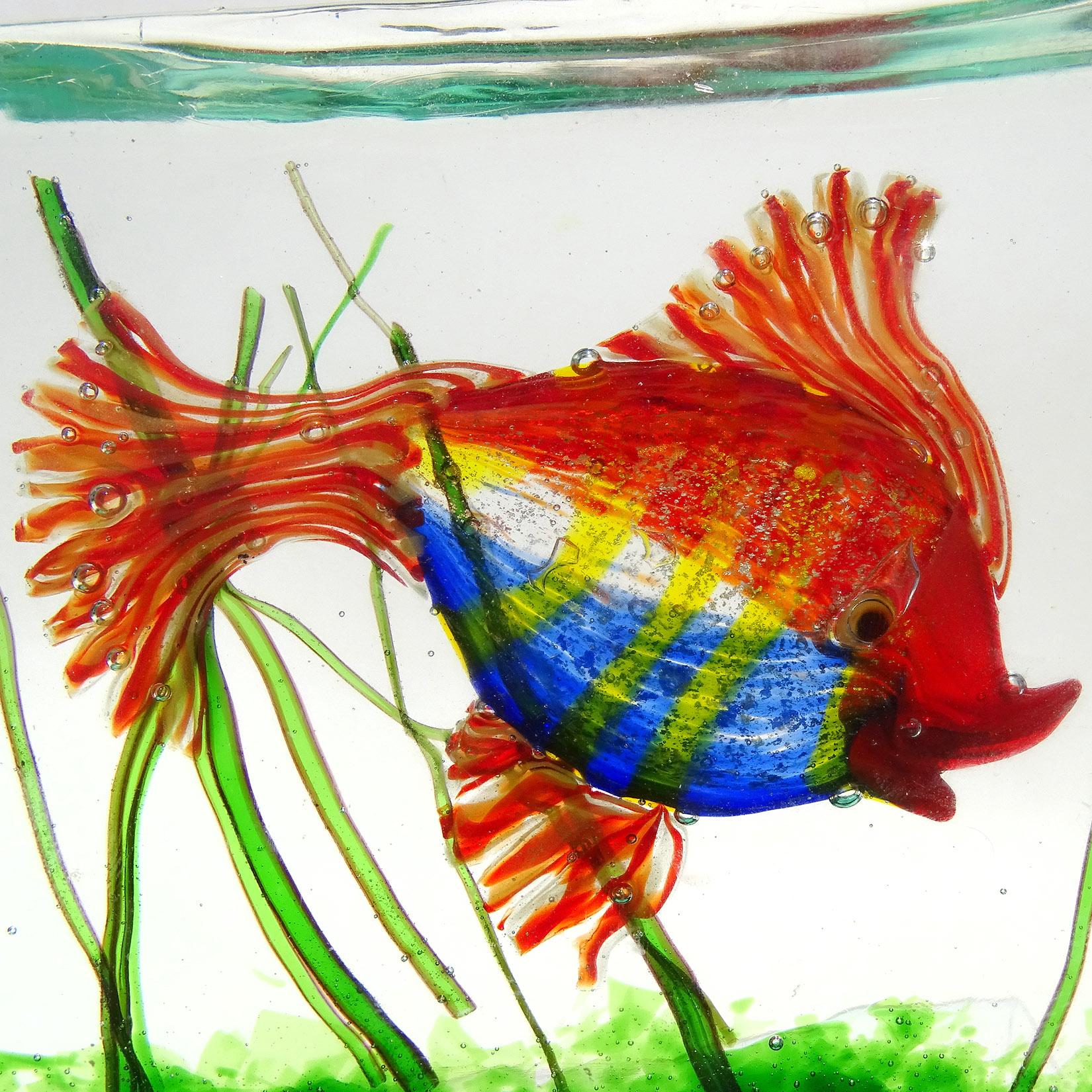 Beautiful vintage Murano hand blown red, blue, yellow stripes, and silver flecks Italian art glass fish aquarium sculpture block. Documented to the Cenedese company, and attributed to designer Alfredo Barbini. The fish has very bright coloration,