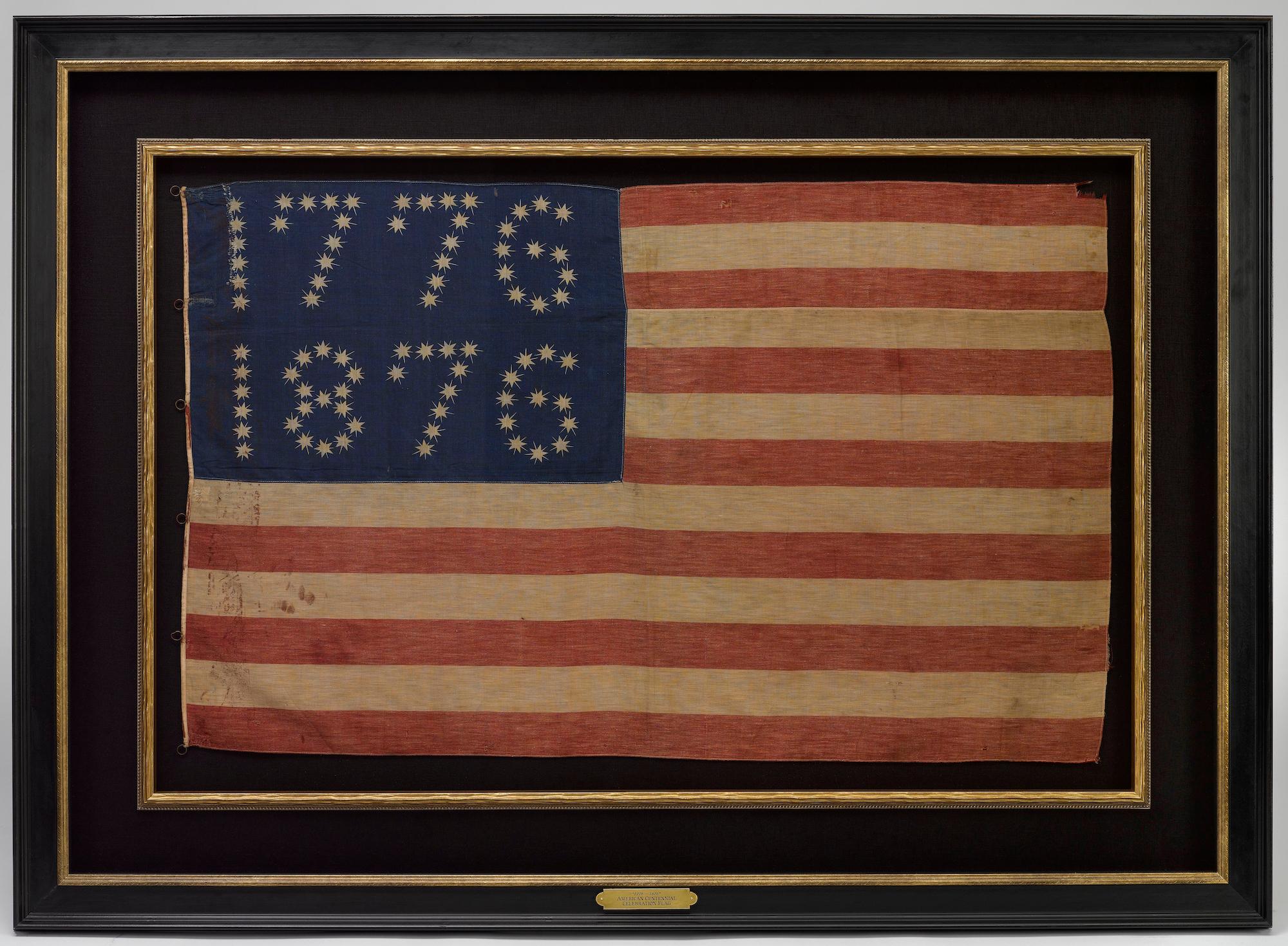Presented is a rare Centennial patriotic flag banner, dating to 1876. The flag’s rich blue canton is spectacular, with 81 five-pointed, rayed stars printed in white and arranged to read “1776” and “1876.” The flag’s design is completed with thirteen