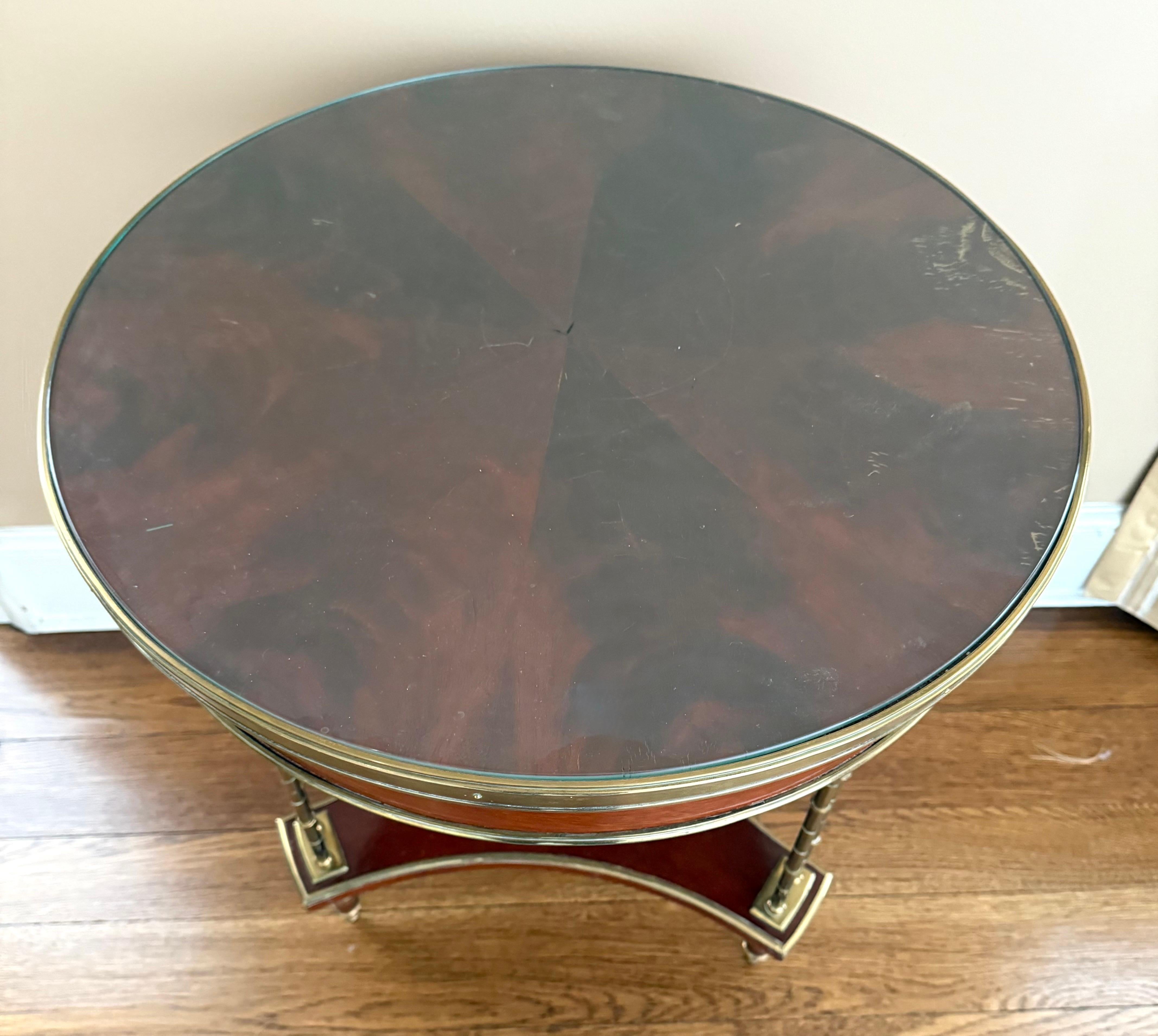 Bouilliote, table d'appoint ou de centre en acajou de style hollywood regency en forme de bambou dans le style de la Maison Jansen. Il est doté de pieds tripodes rares, d'un tablier encadré de bronze et de lignes à couper le souffle ! Pourquoi ne