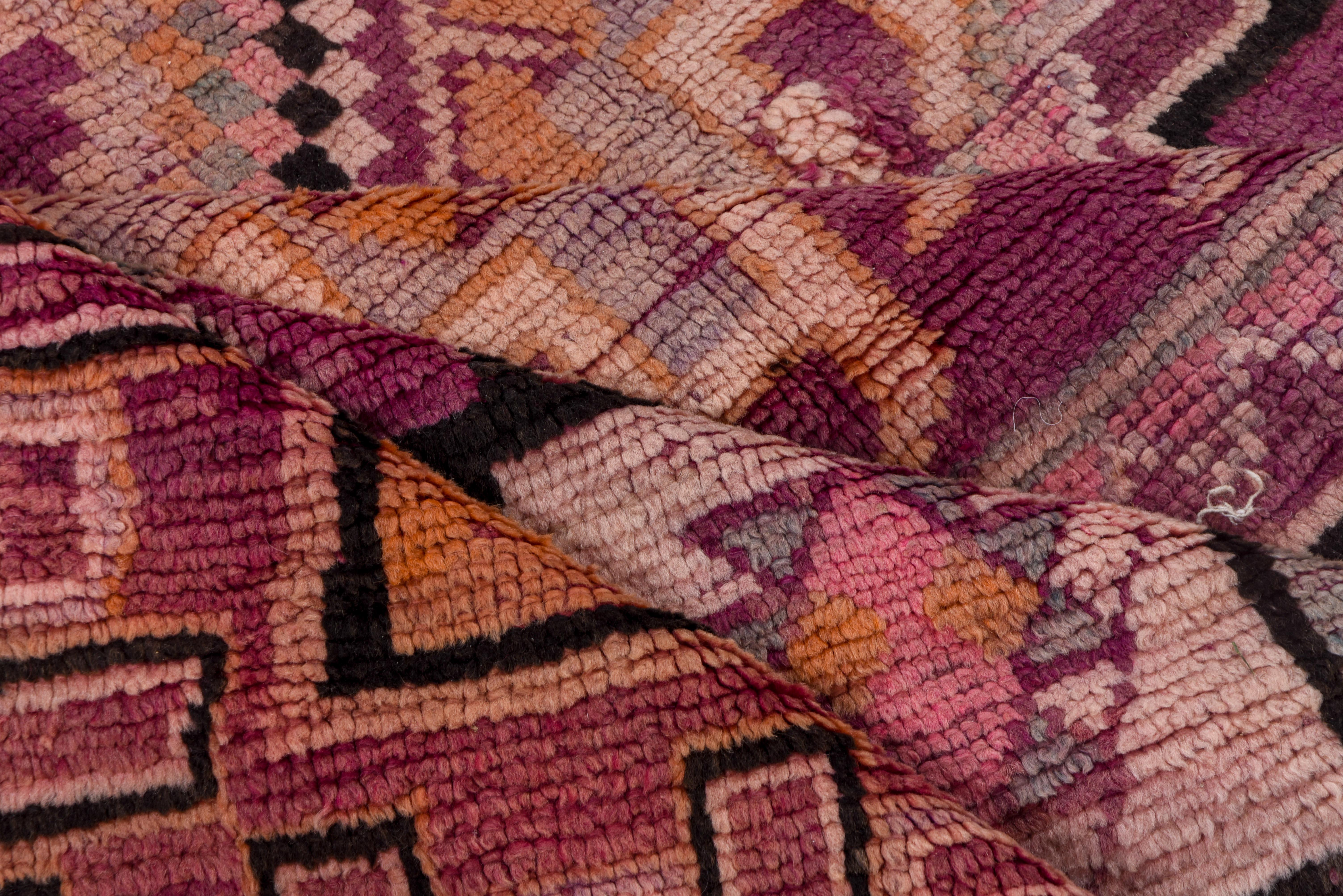 This Moroccan village rug features a large medallion design on the centerfield - with smaller, more accented, repeating diamond motifs acting as a border to the central design. This rug is purple with other like dark colors. 