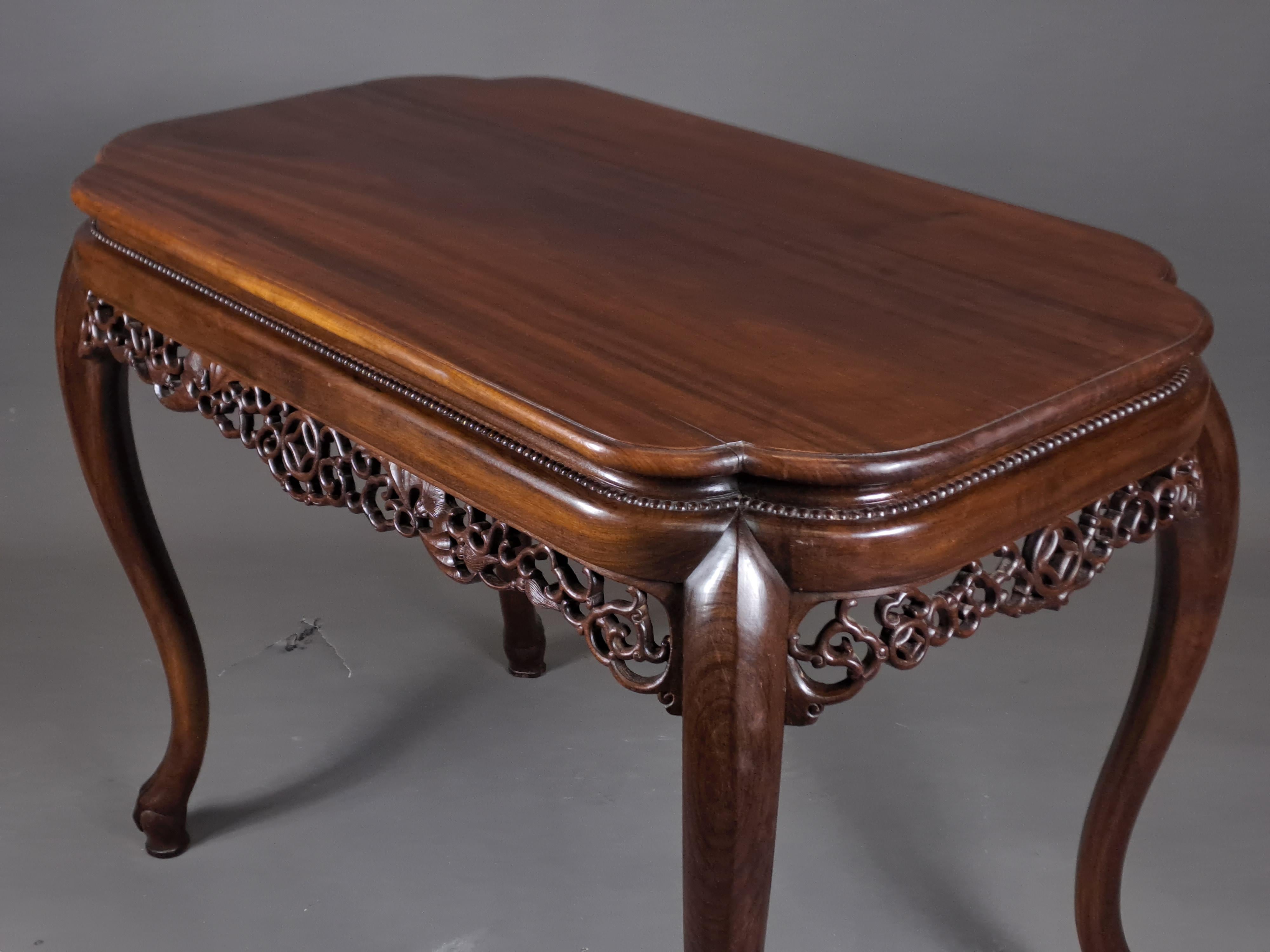 Beautiful center table in solid mahogany richly carved on the belt of scrolls and bats, top with scalloped corners surmounted by an ogee acroterion decorated with a beaded frieze.

Four curved legs ending in the shape of eagle claws holding a