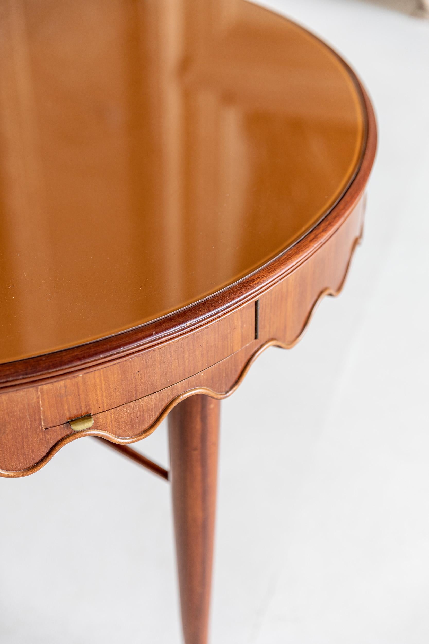 Rare and elegant center or game table attributed to Osvaldo Borsani.
Very elegant structure, original pink painted glass top.
Four little drawers with 2 ashtrays.