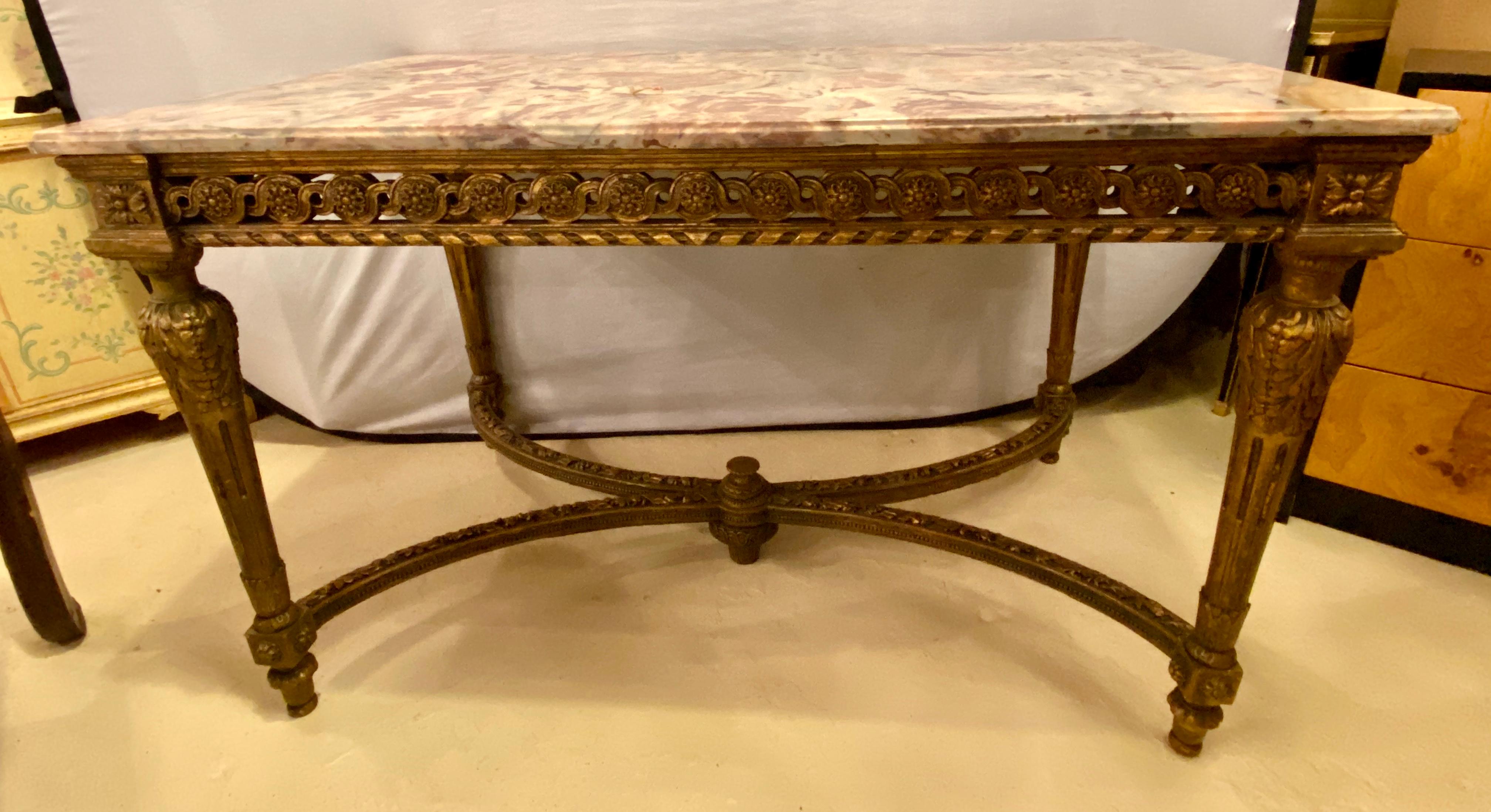 Stamped Jansen center table having a gilt base and fine pink, grey and white veined marble-top. The top having been professionally repaired. The Louis XVI style center table having been antique guided. The four corner legs supported by X-form carved