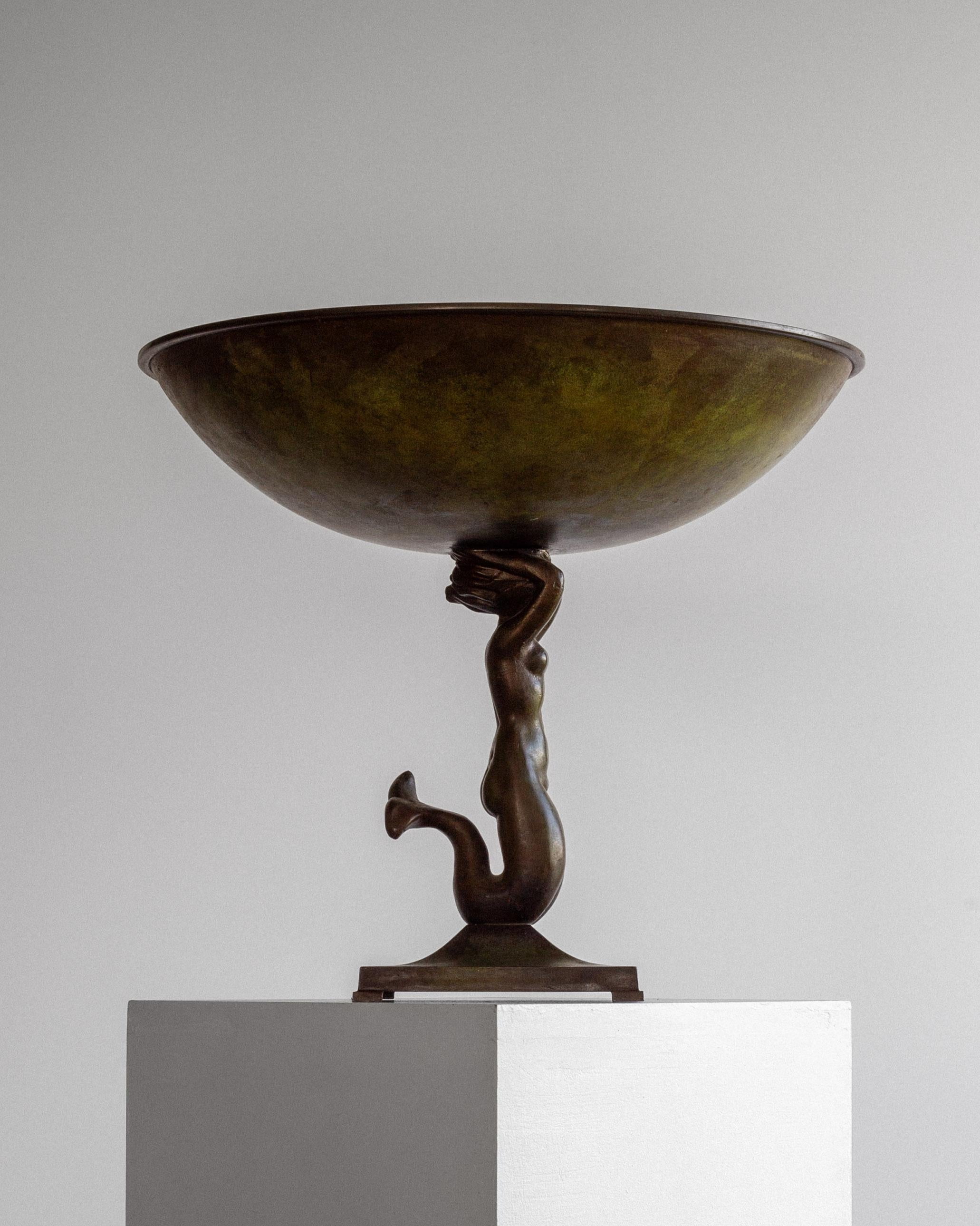Grande ciotola Art Déco su piede, realizzata dall'importante azienda svedese Ystad Brons negli anni Trenta. Fuso in bronzo con una ricca finitura patinata dai toni verde scuro e bronzo, il pezzo mette in mostra una graziosa sirena come supporto