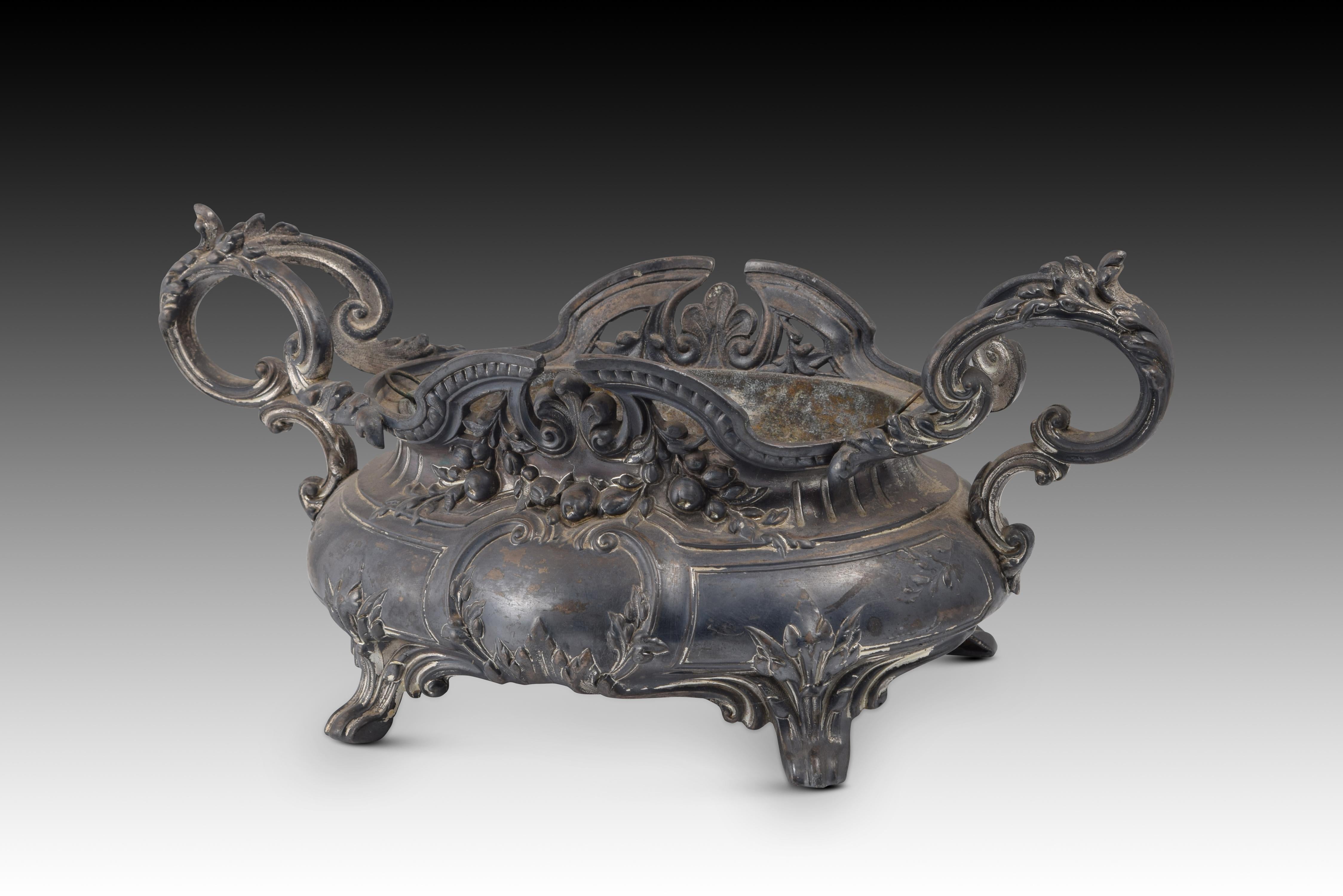 Centerpiece. calamine. France, 19th century. 
Centerpiece made of calamine slightly raised on legs and that has two handles on the sides. The elaborate and delicate decoration based on architectural elements, garlands, plant motifs and scrolls (all