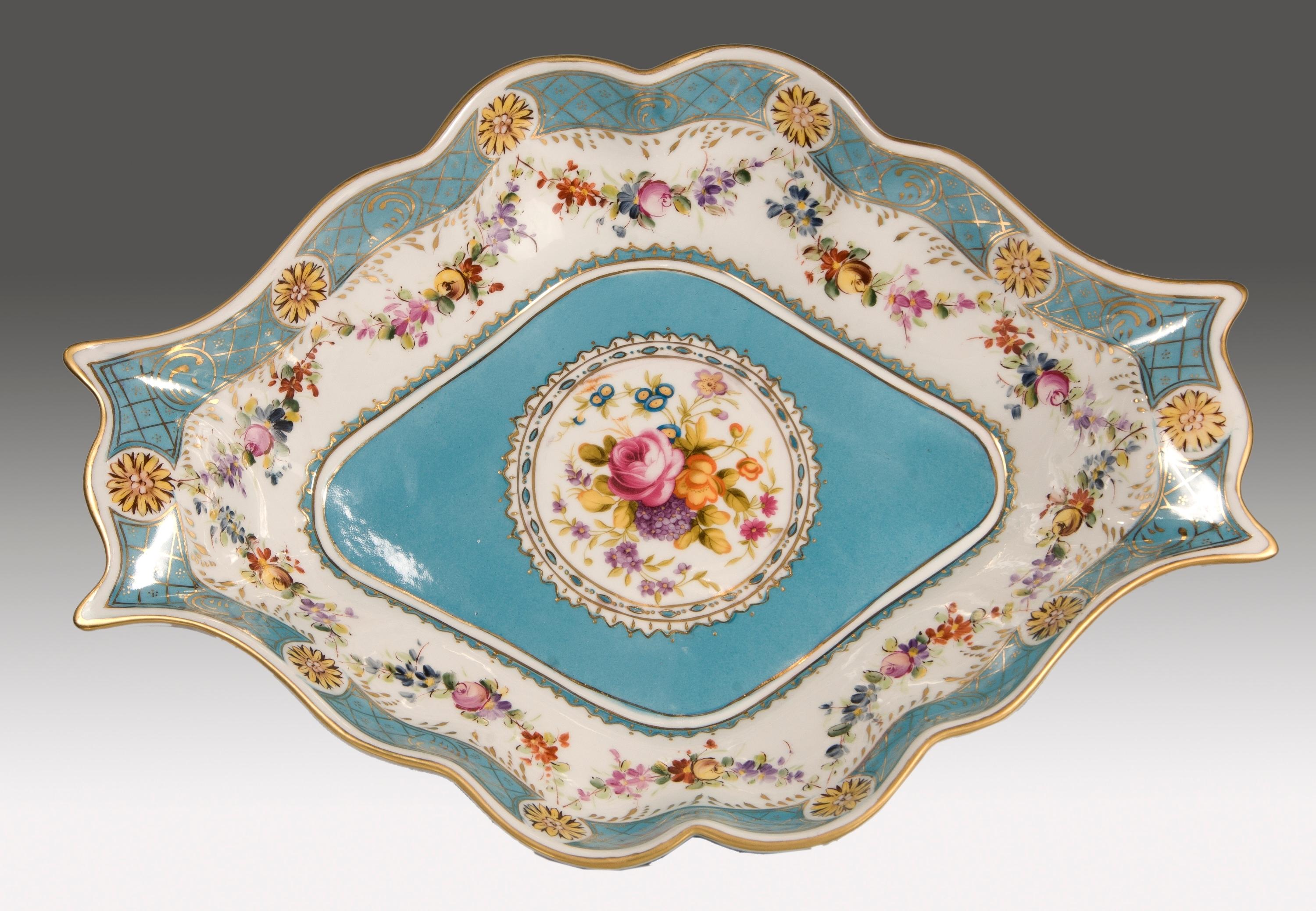 Centerpiece. Glazed porcelain.
Enameled porcelain centerpiece slightly raised on four volute-shaped legs and plain blue mirrors in front. The curved profiles, extended towards the neck, remind of examples inspired by the Rococo, while the