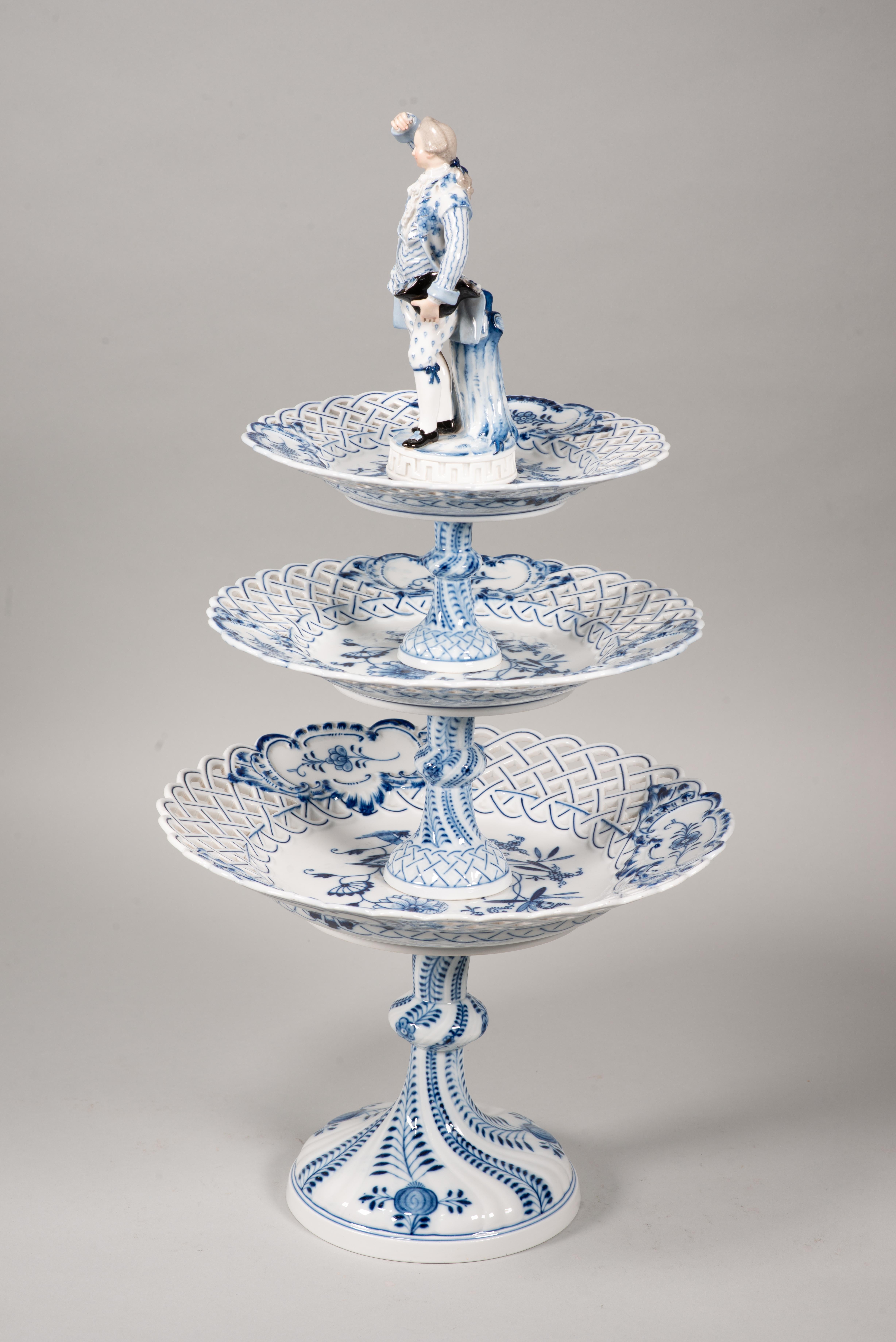  Centerpiece. Glazed porcelain. Meissen, Germany, possibly second half of the 19th century. 
With marks and numbers on bases. Maybe small faults.
Enameled porcelain centerpiece topped with a male figure dressed in 18th century European fashion. It