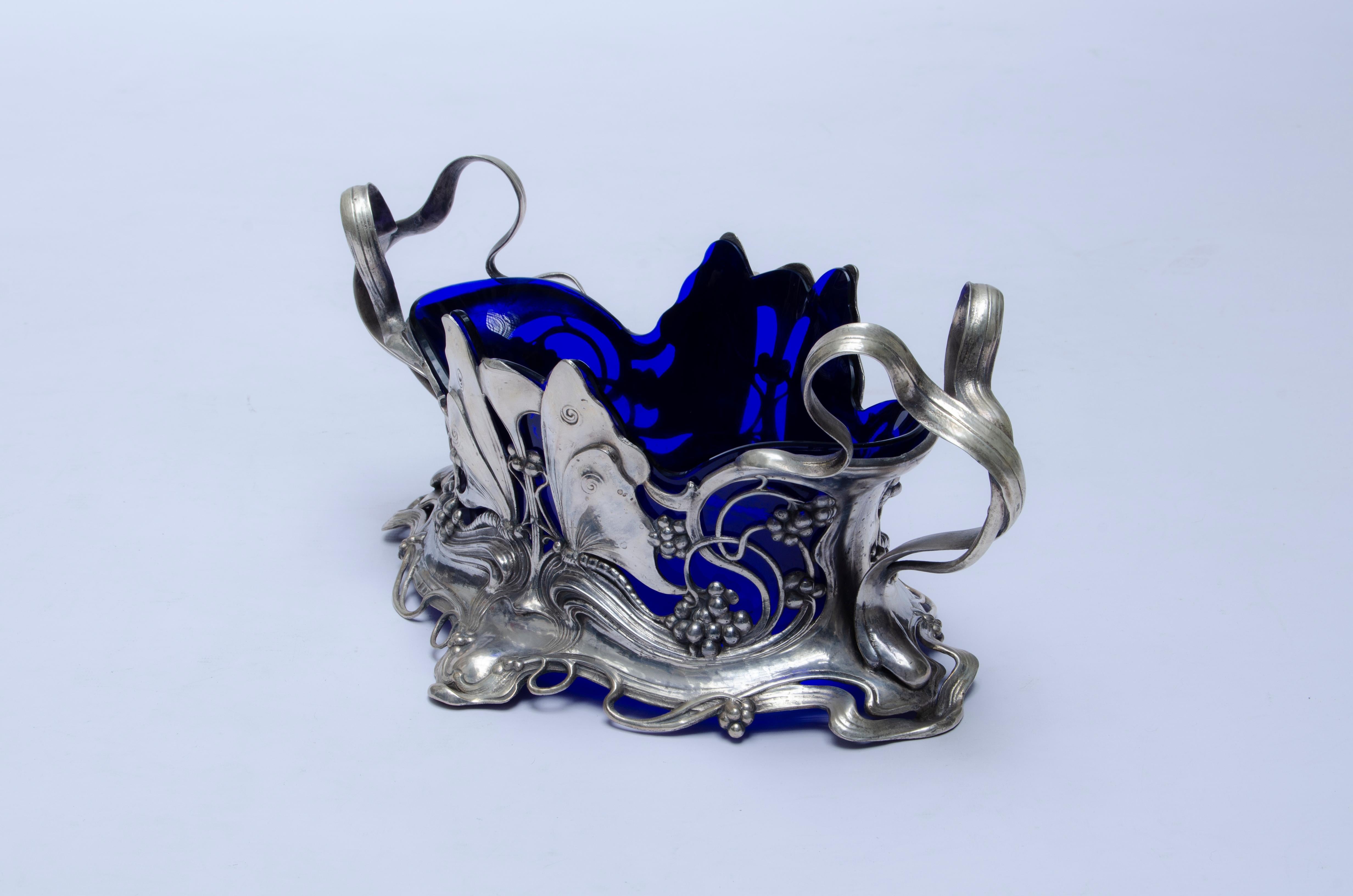 Centerpiece made of silver plated pewter and blue glass. Manufactured by WMF-Württembergische Metallwarenfabrik (1853 - present).

Graham Dry (1996), “Art Nouveau Domestic from Württembergische Metalwarenfabrik”. Model 131, p-295.

Germany, CIRCA