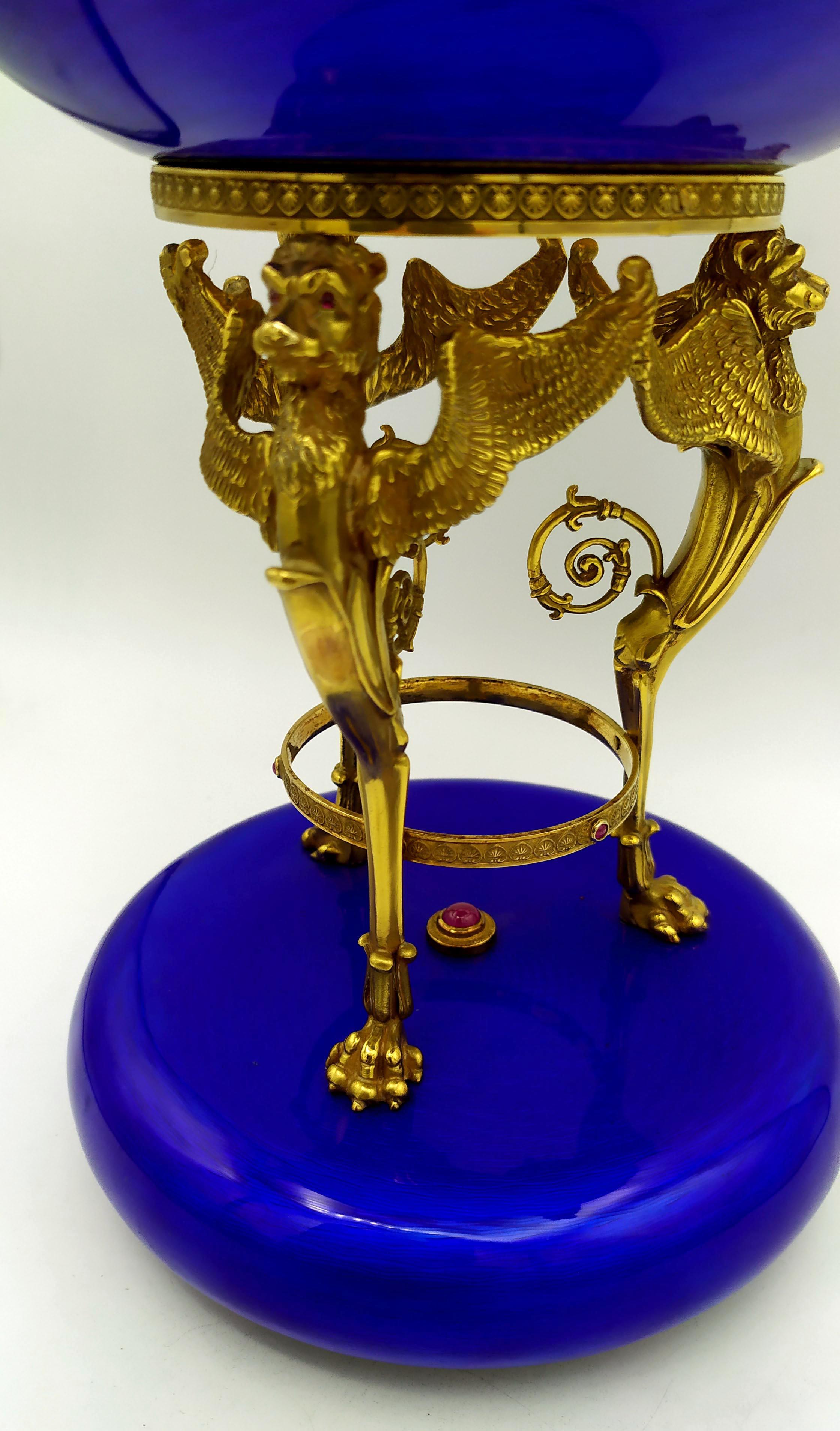 Large centerpiece in 925/1000 sterling silver gold plated with translucent fired enamel on guilloche. Round base with rounded edge, diameter 15 cm, height 3.5 cm, with sculptures of 3 winged lions, height 13 cm, holding a bowl with diameter 18 cm,