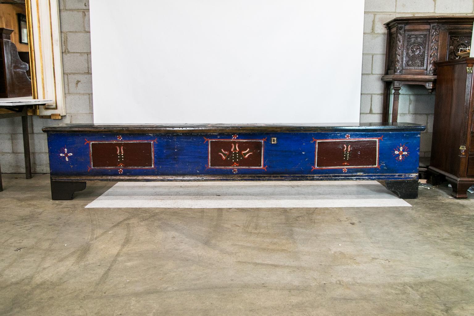 This Central European long painted blanket chest has three floral painted panels on the top and the front. The interior has three separate compartments with the original steel lock.
 