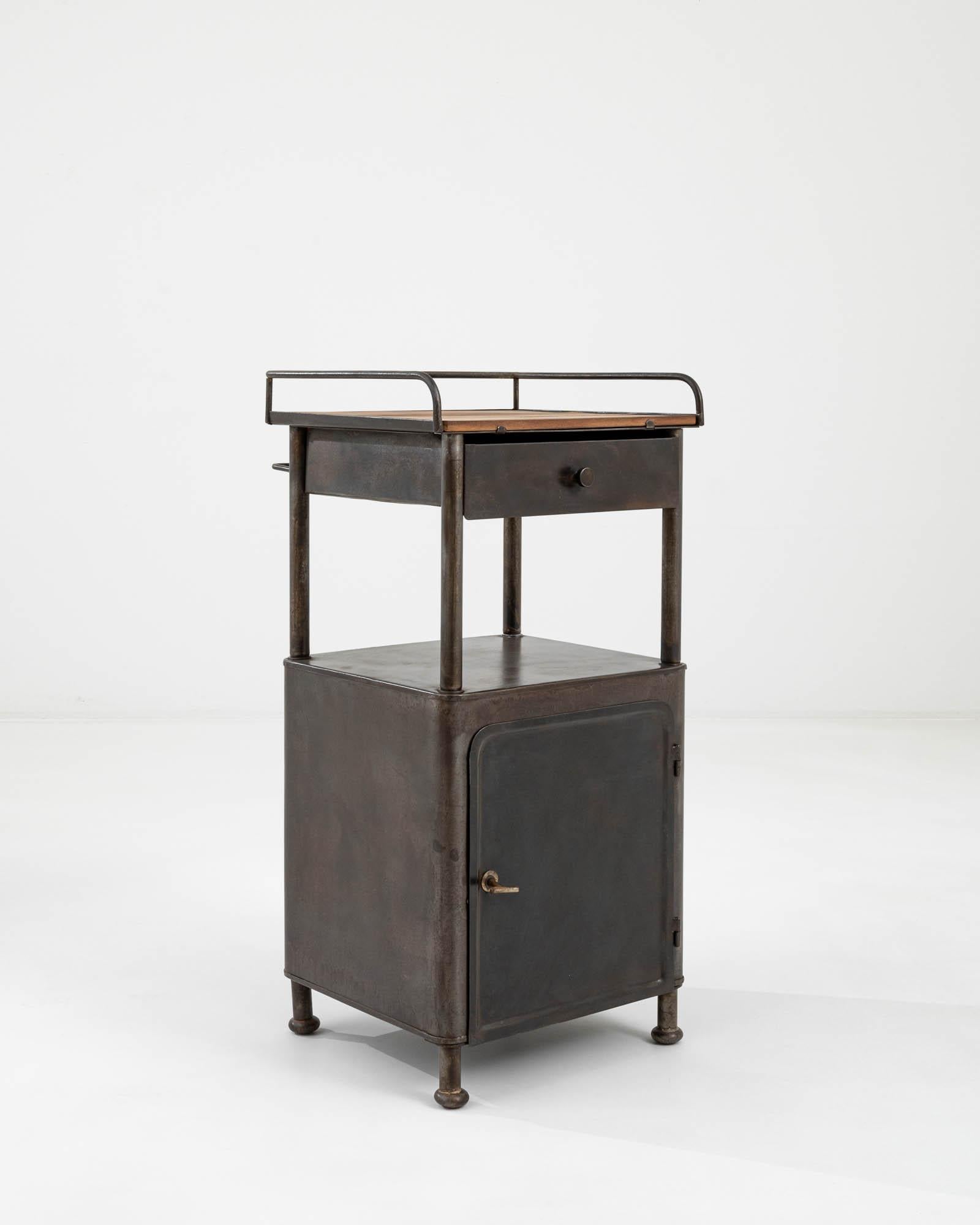 This metal side table was crafted in the Czech Republic circa 1950 – embodying the futurist spirit of industrialization. Elevated on tubular legs, the table features a convenient compartment with a door and a sliding drawer with a wood tablet on the