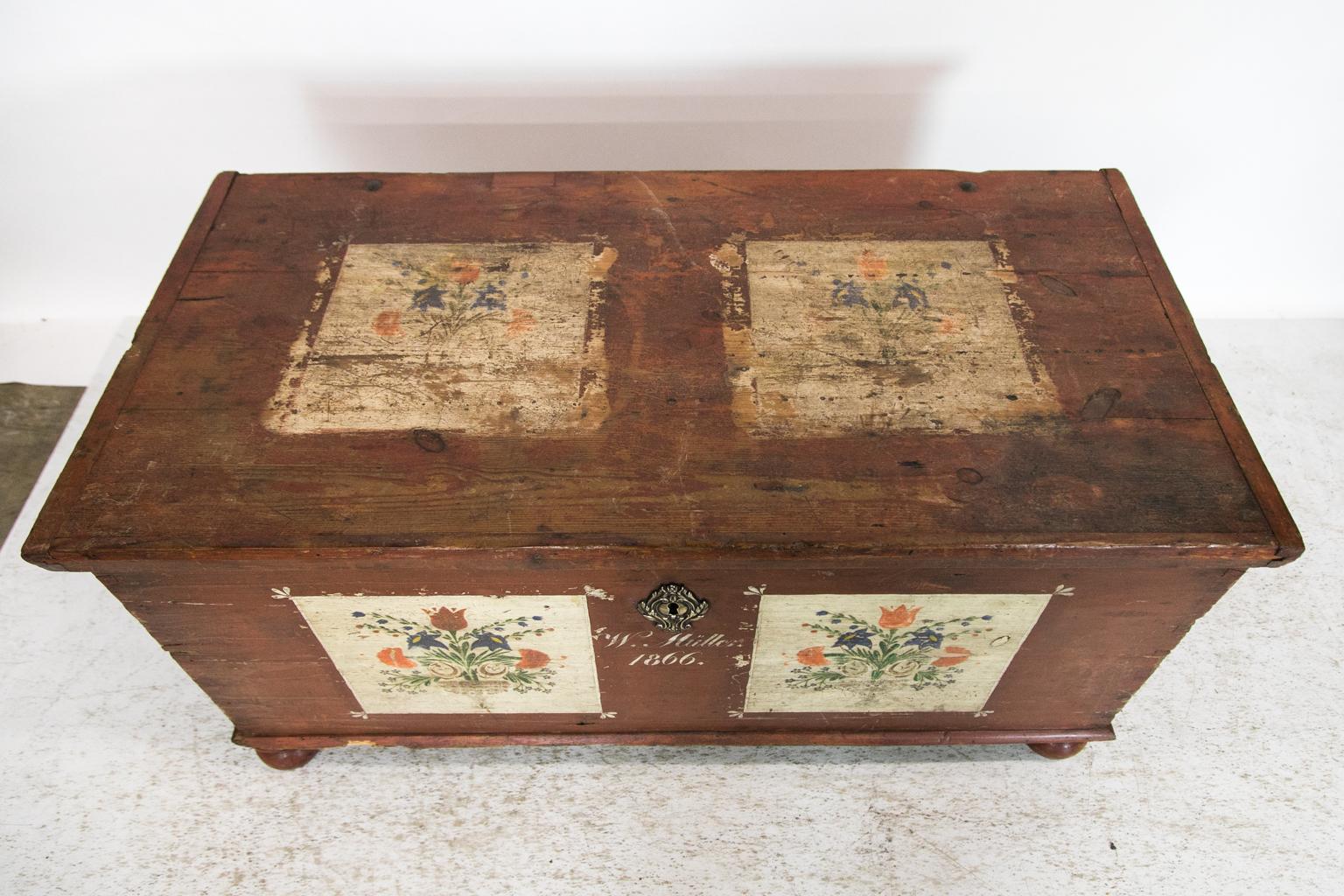 The top and bottom of this blanket chest have the original red paint and floral panels on the front. It is signed on the front: 